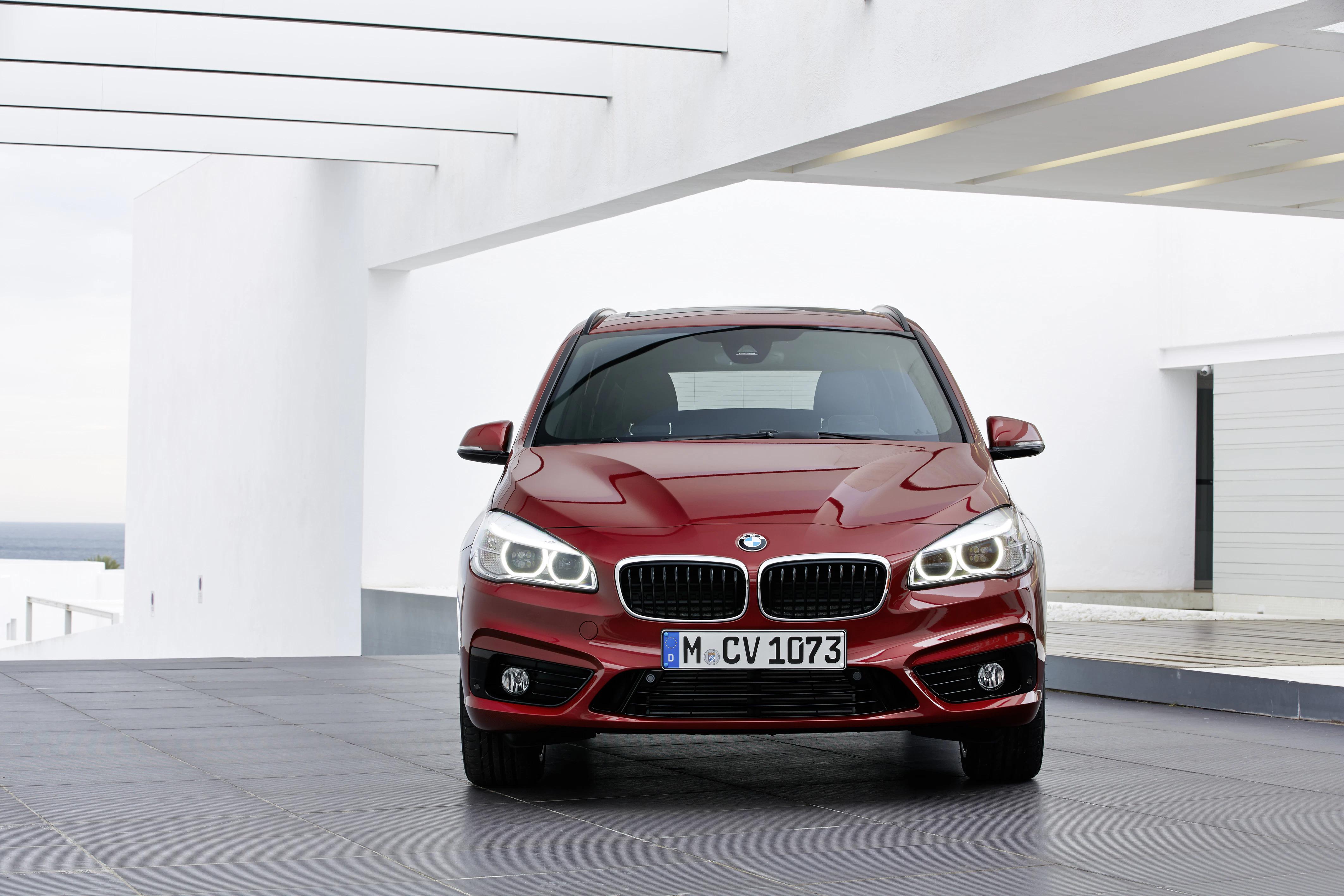 Roter BMW, Frontansicht, auf einer modernen Terrasse mit schlichtem Hintergrund und klaren Linien.