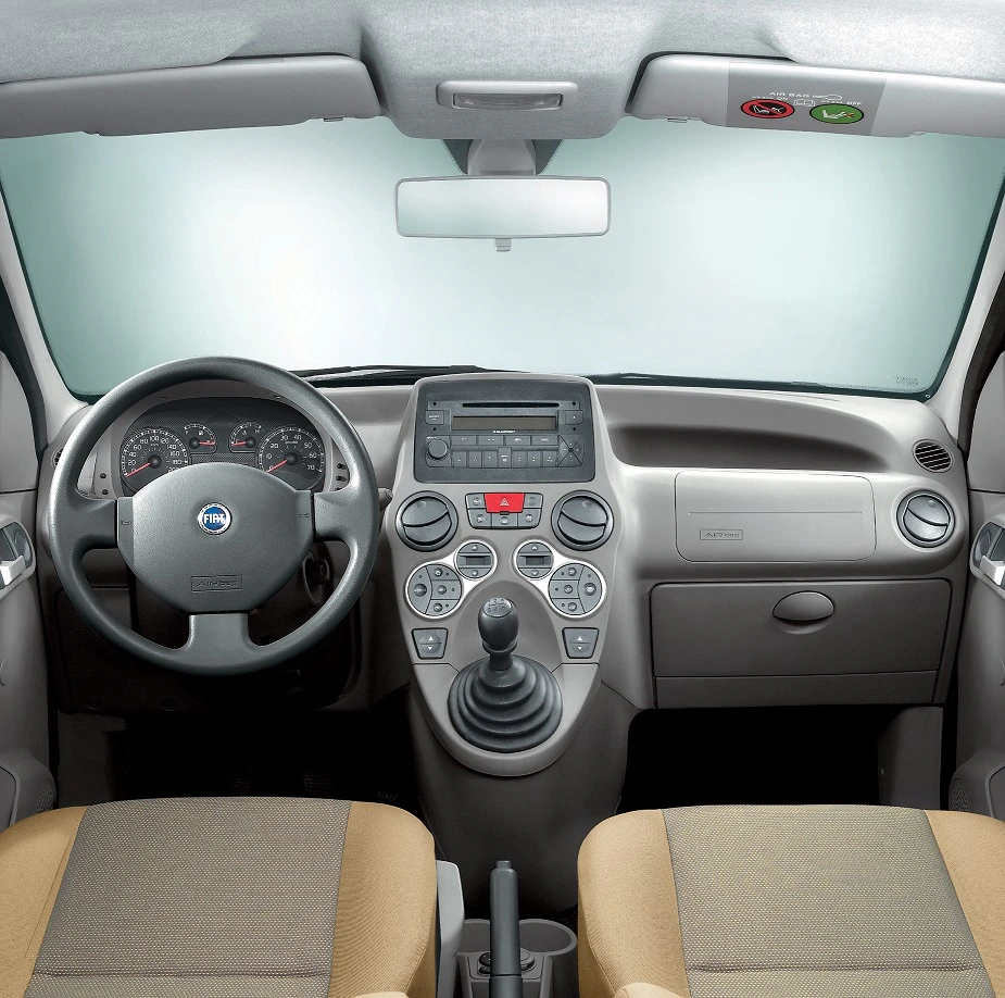 Innenraum eines Autos mit grauem Armaturenbrett, Lenkrad, Schaltknüppel und zwei beigefarbenen Sitzen. Ansichten von vorn.