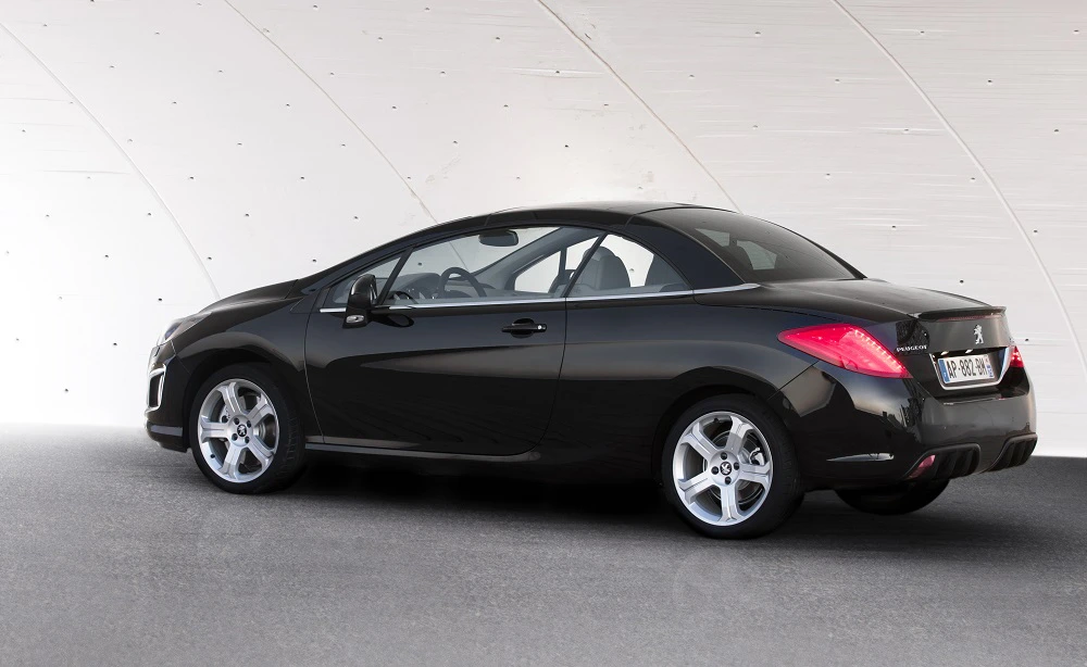Schwarzes Peugeot Cabriolet auf grauem Untergrund, seitlich von hinten gezeigt. Elegantes Design mit geschlossenen Verdeck.