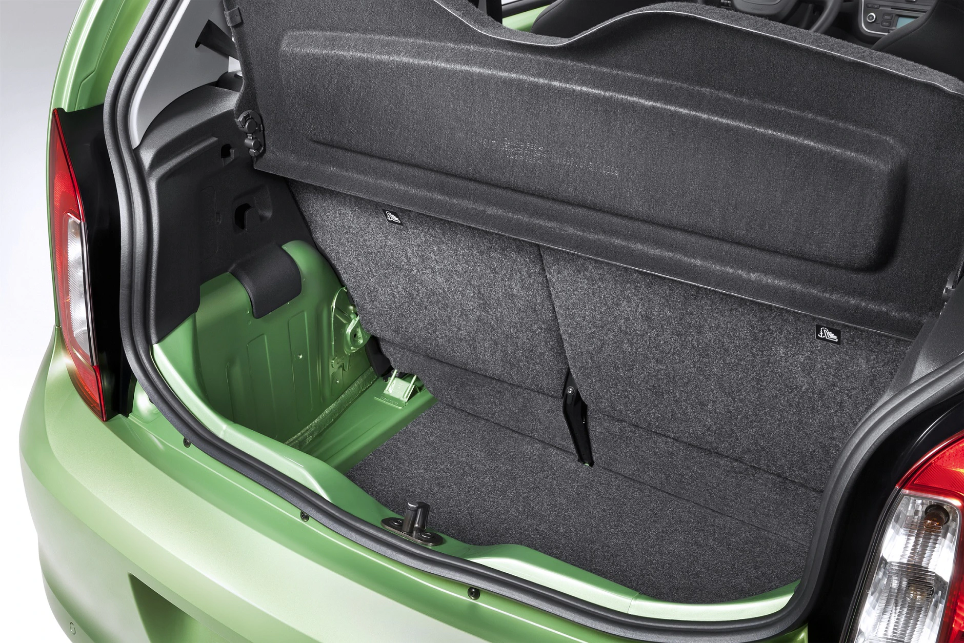 Kofferraum eines grünen Autos mit umgeklappten Rücksitzen, viel Stauraum und grauem Innenraum.