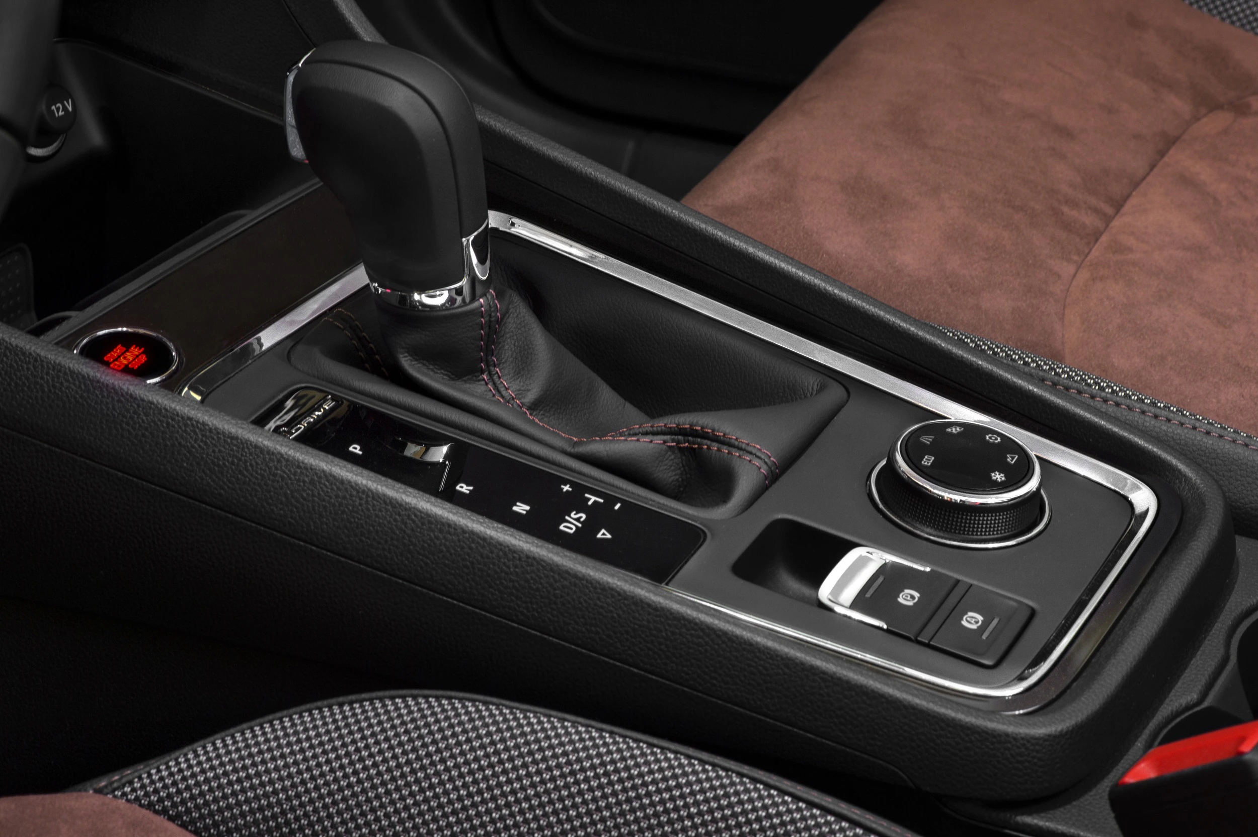 Nahaufnahme einer schwarzen Automatikschaltung in einem modernen Auto, umgeben von eleganter Innenausstattung in dunklen Farbtönen.