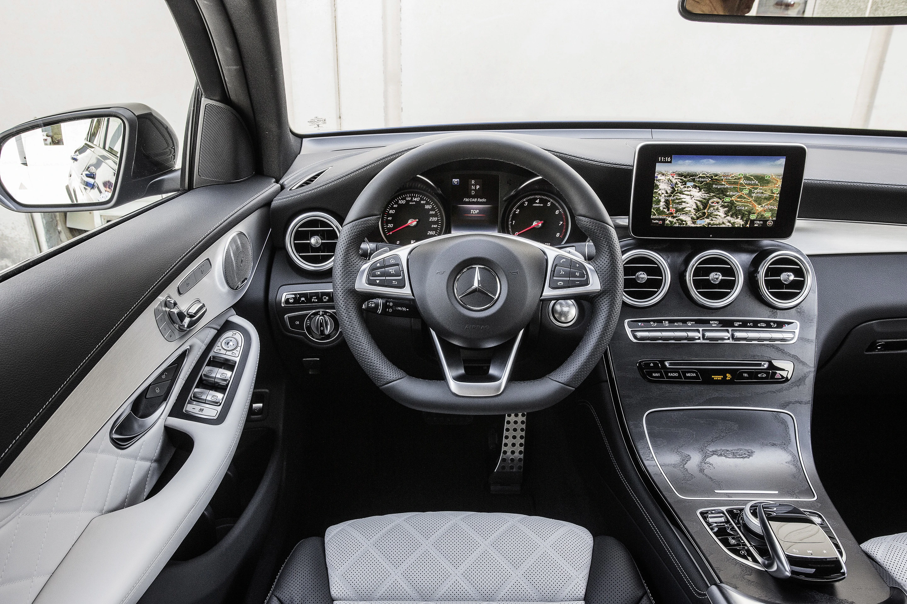 Innenraum eines Mercedes mit Lenkrad, Armaturenbrett und Navigationssystem. Hochwertige Materialien und modernes Design.