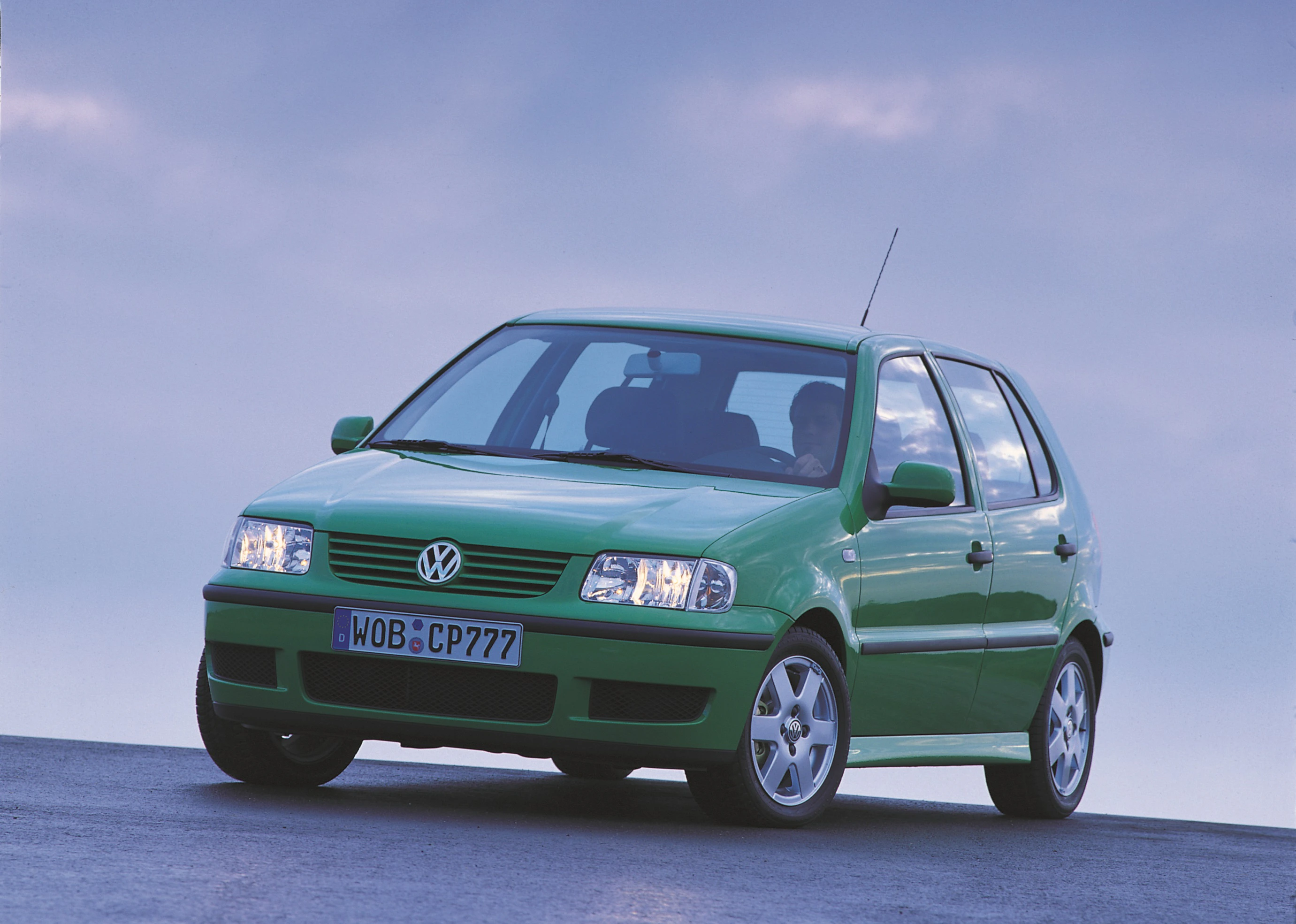 Grüner Volkswagen Polo auf einer Straße vor blauem Himmel. Der Wagen zeigt die Front und Fahrer-Seite.