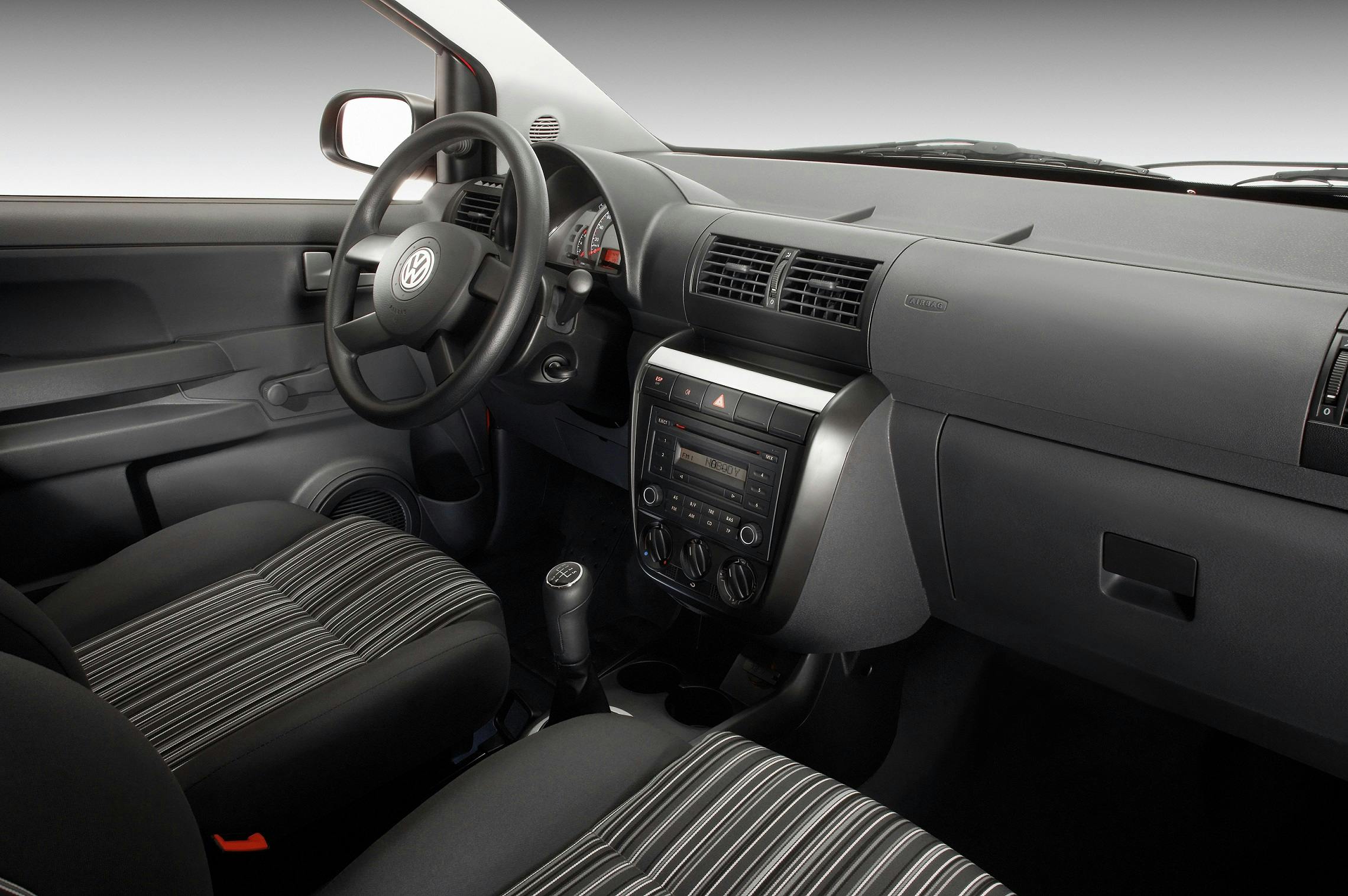 Innenraum eines Autos mit schlichter Ausstattung. Sichtbar: Lenkrad, Armaturenbrett und Sitze mit gestreiftem Muster.