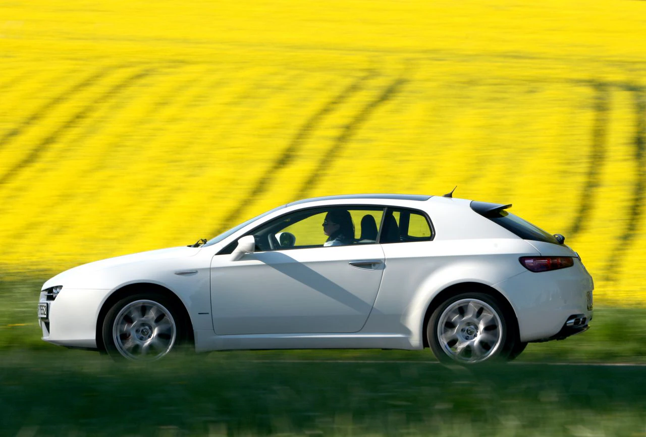 Weißes Auto fährt an gelbem Rapsfeld vorbei, unscharfer Hintergrund, klarer Himmel.