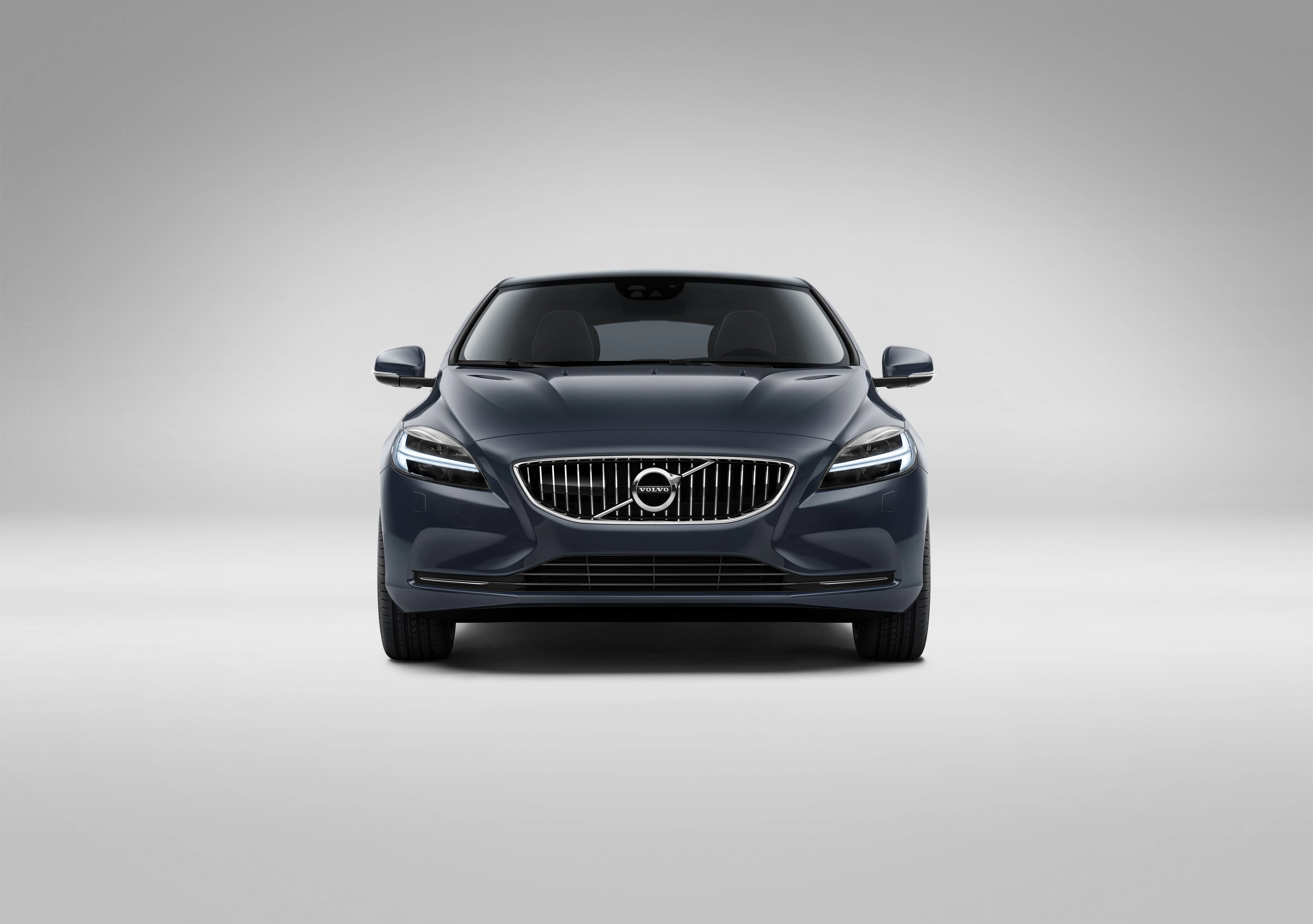 Frontansicht eines grauen Volvo Autos auf grauem Hintergrund, moderne Scheinwerfer und markanter Kühlergrill erkennbar.