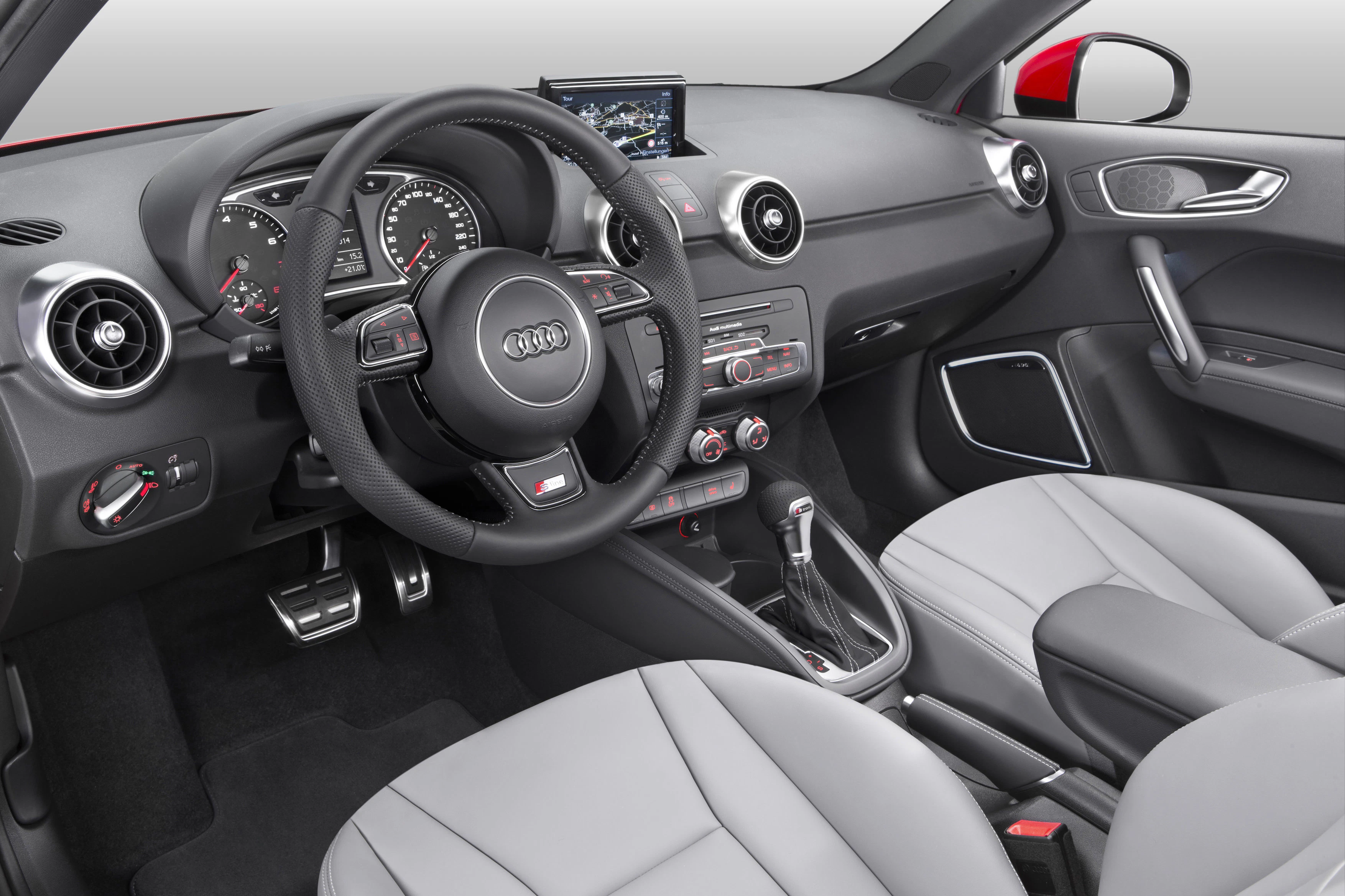 Innenraum eines Audi-Autos mit grauen Ledersitzen, modernem Armaturenbrett, Multifunktionslenkrad und zentralem Display.