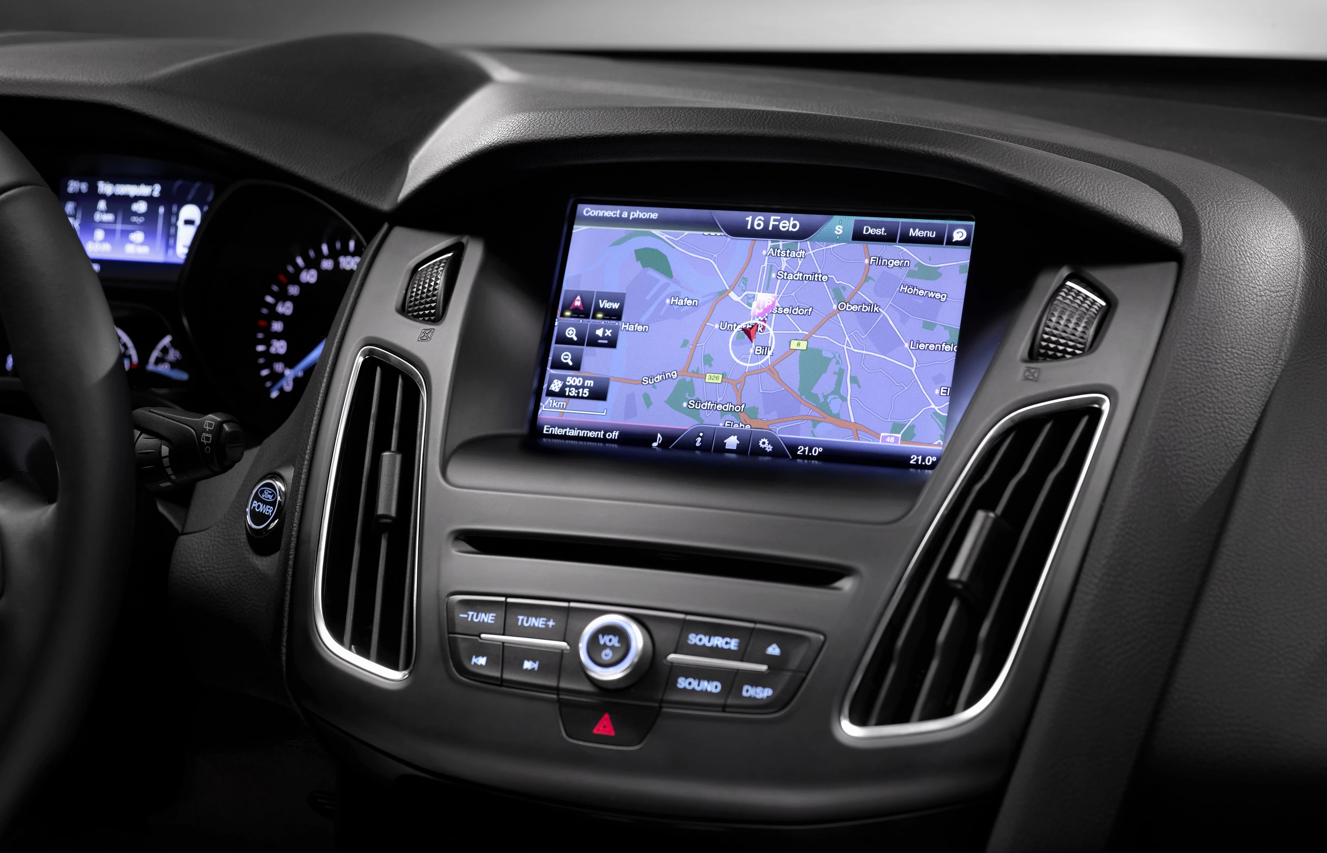 Nahaufnahme eines Autoinnenraums mit GPS-Navigationssystem auf dem Bildschirm. Das Armaturenbrett zeigt Bedienelemente und Tachometer.