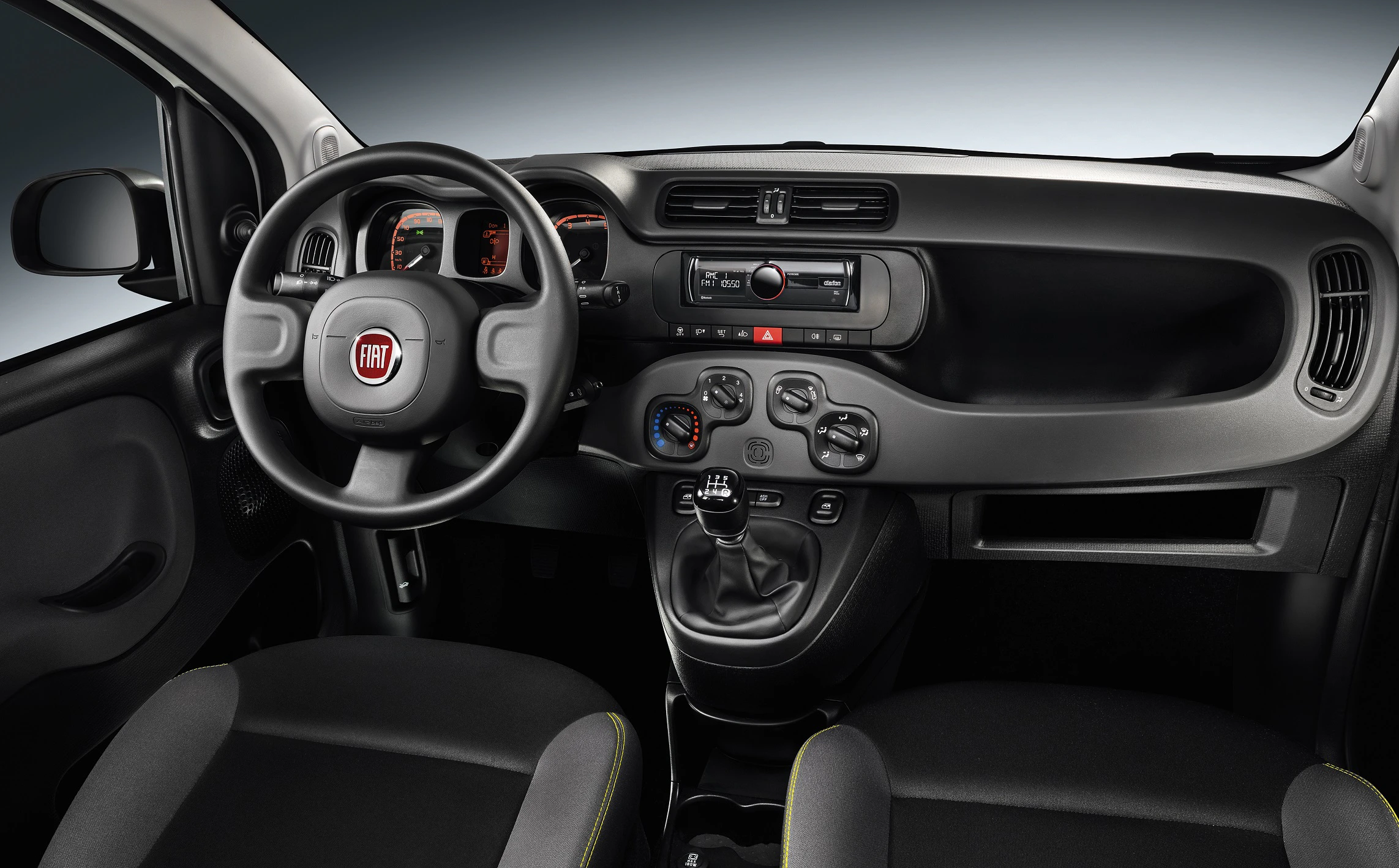 Innenraum eines Fiat-Autos mit Lenkrad, Armaturenbrett und Schalthebel; schwarze Ausstattung mit modernen Instrumenten und Bedienelementen.