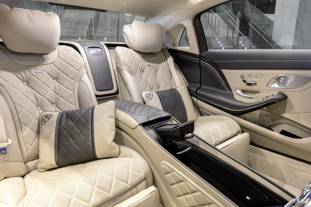 Luxuriöses Auto-Innenraum mit beigen Ledersitzen, dunklen Akzenten und gesteppten Kissen. Elegantes Design mit modernen Details.