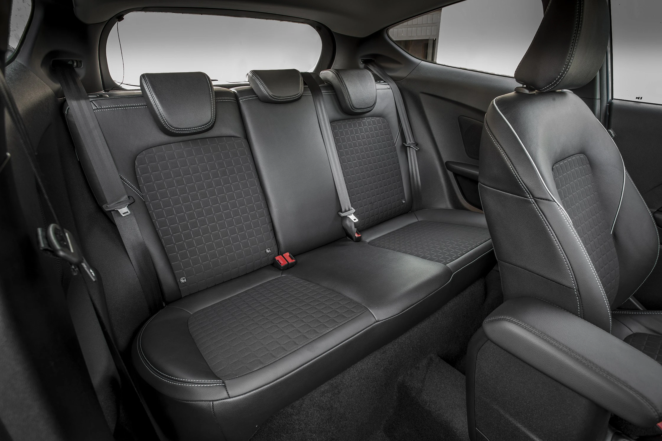 Rücksitz eines Autos mit grauen, gepolsterten Sitzen und Sicherheitsgurten, moderner Innenraum.