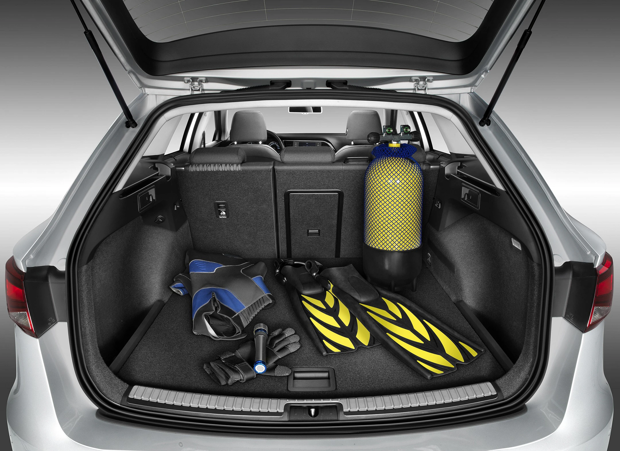 Kofferraum eines Autos mit Tauchausrüstung: Flossen, Taucheranzug, Schnorchel und gelber Sauerstofftank.