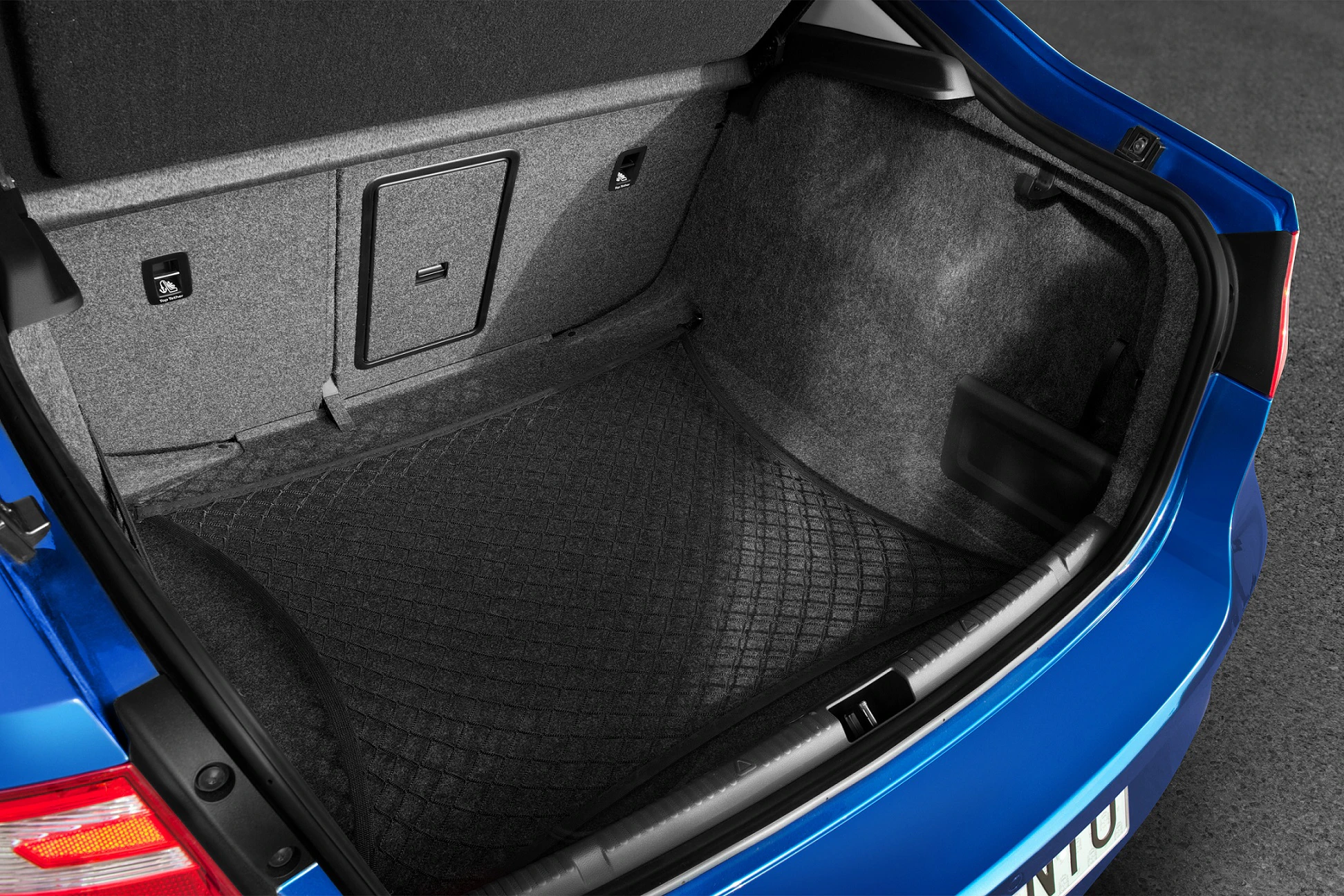 Offener Kofferraum eines blauen Autos mit grauer Innenverkleidung und gemustertem Kofferraumteppich.