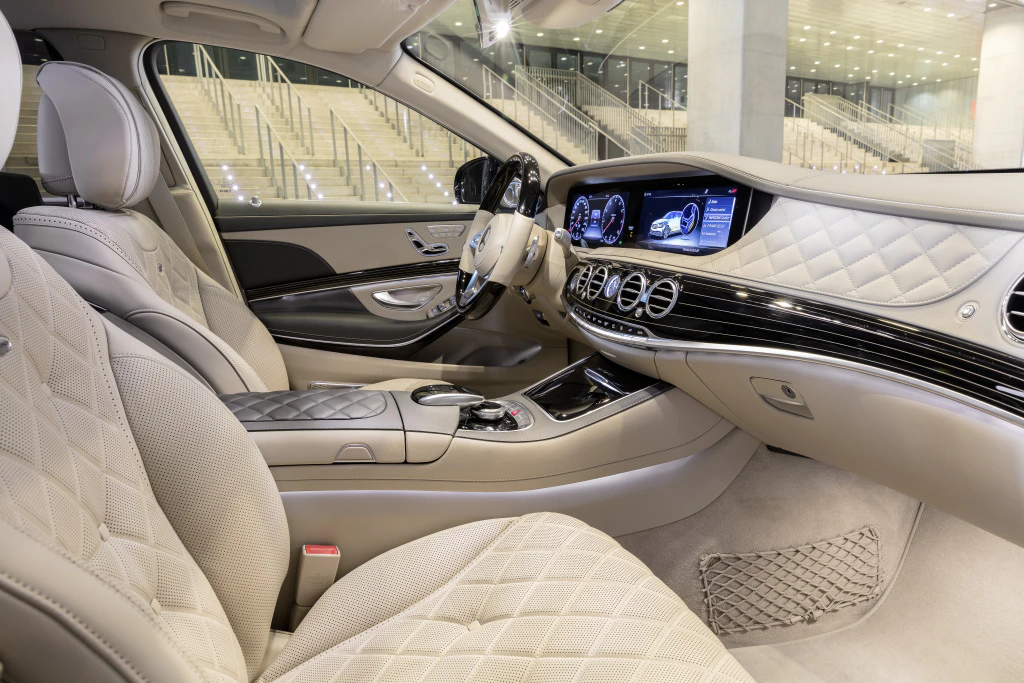 Luxuriöser Autoinnenraum mit beiger Lederausstattung, digitalem Armaturenbrett und eleganten Details unter hellem Showroom-Licht.