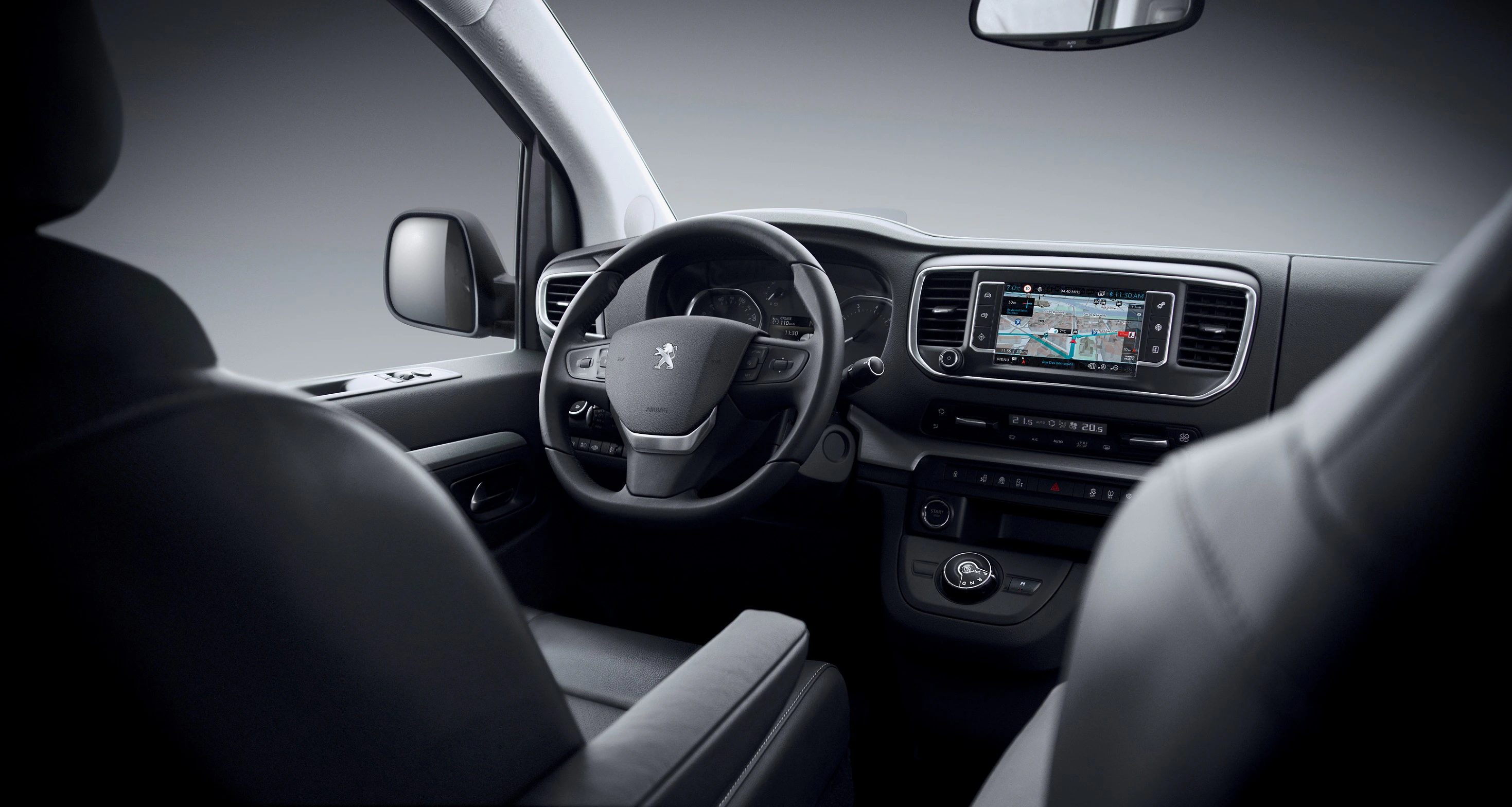 Innenraum eines Autos mit schwarzem Lenkrad, Touchscreen-Navigationssystem und komfortablen Sitzen. Modernes Design und hochwertige Ausstattung.