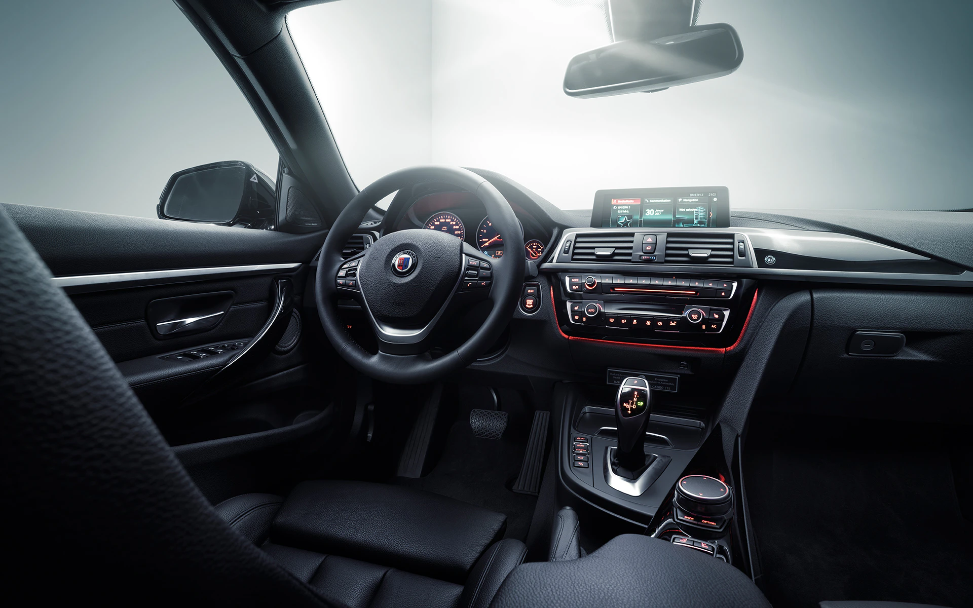 Innenraum eines modernen Autos mit Ledersitzen, Multifunktionslenkrad, digitalem Display und Ambientebeleuchtung in Rot.