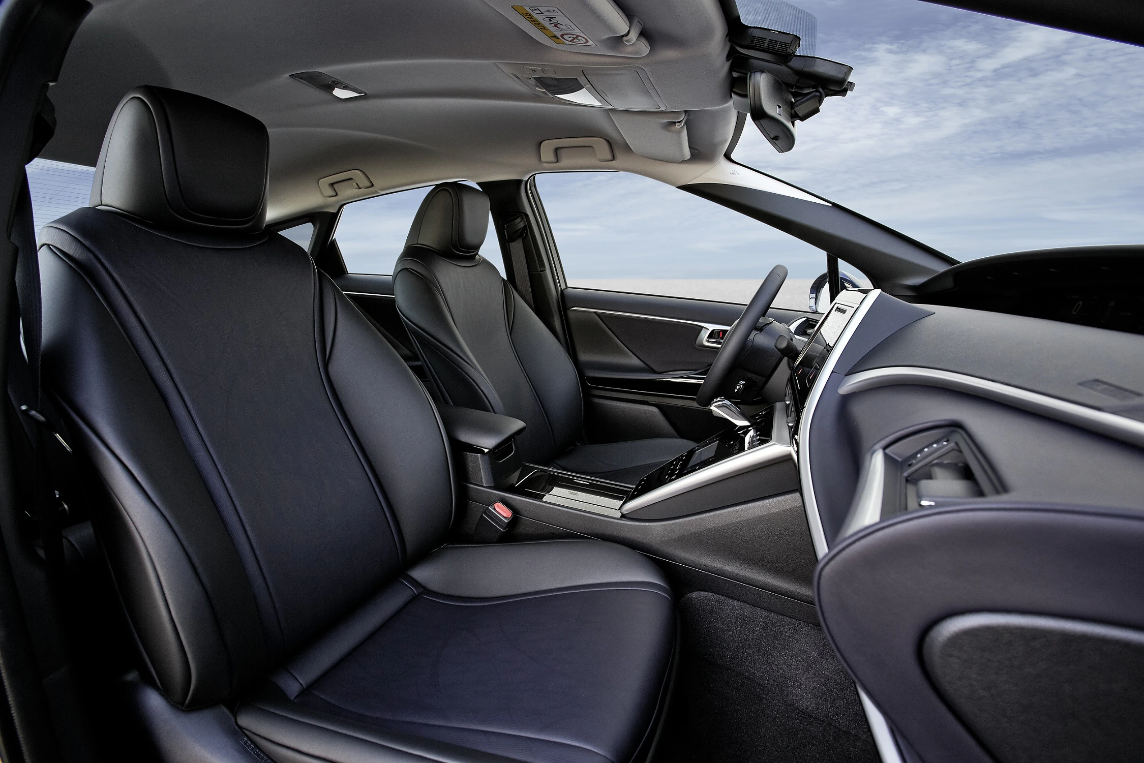 Innenraum eines Autos mit luxuriösen schwarzen Ledersitzen und modernem Armaturenbrett, Blick auf den Himmel durch die Fenster.