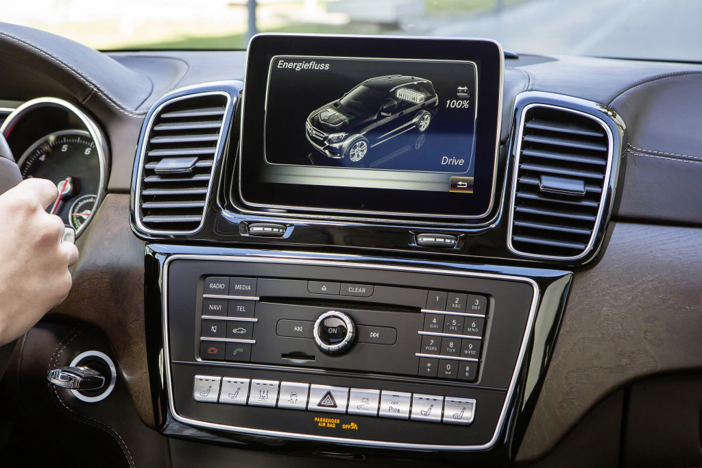 Innenraum eines Autos mit Multimedia-Display, das den Energiefluss und Fahrzeugstatus anzeigt. Fahrerhand am Lenkrad.