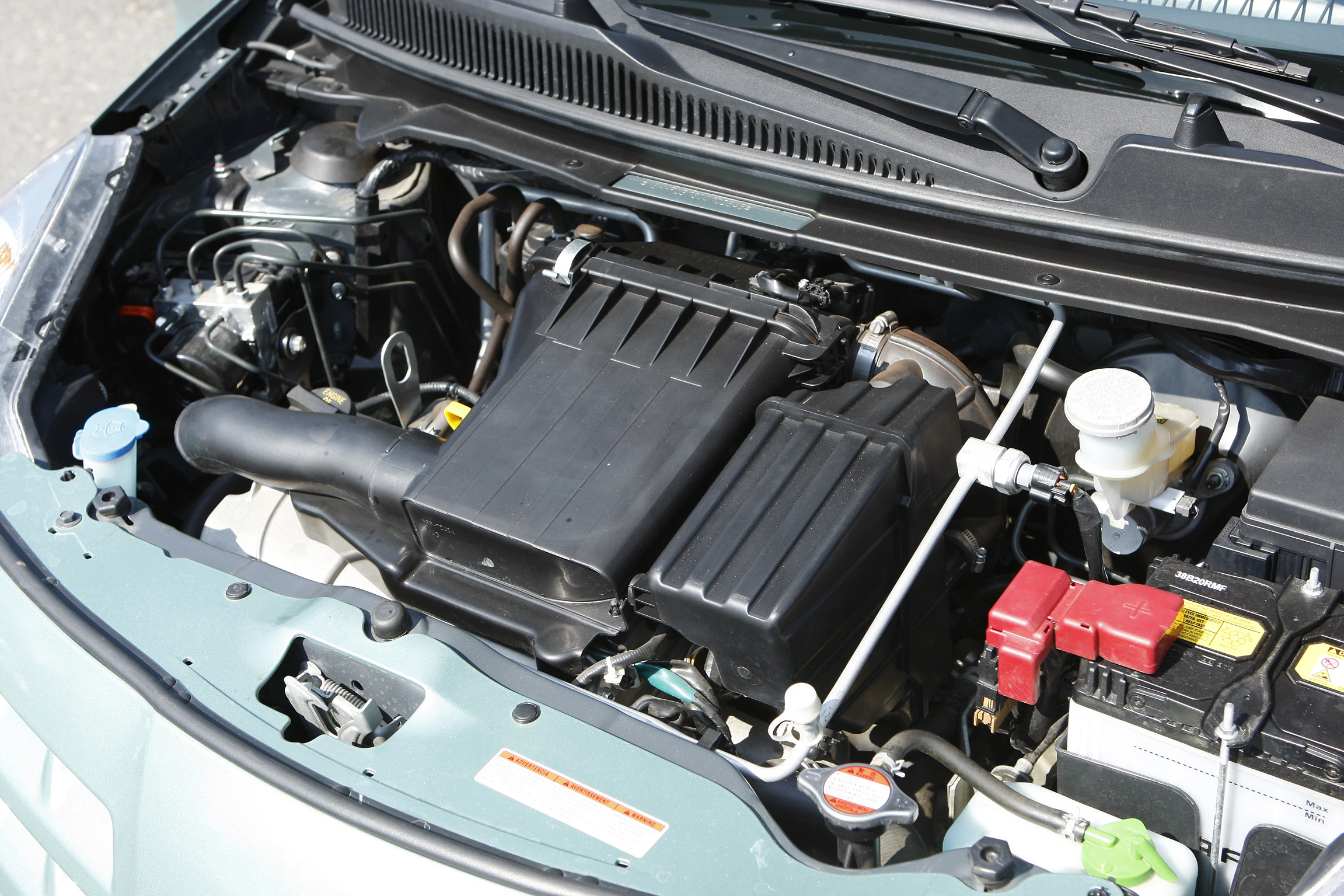 Geöffnete Motorhaube eines Autos, die den Motorraum zeigt. Sichtbar sind verschiedene Motor- und Antriebskomponenten.