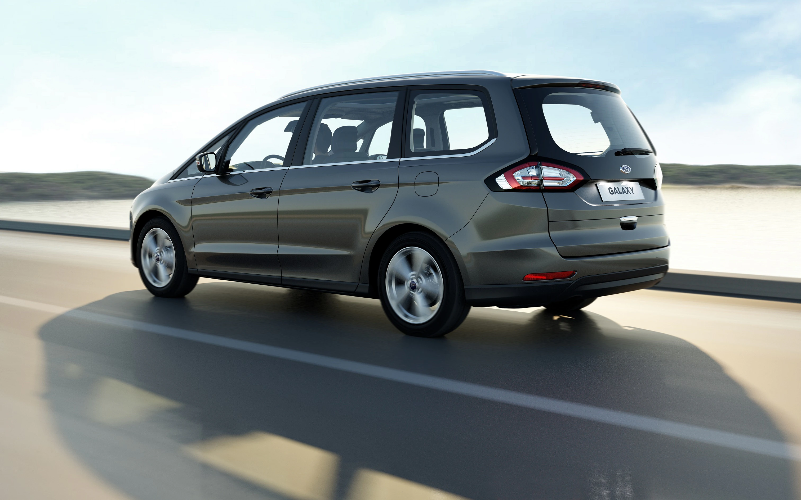 Ein grauer Ford-Galaxy-Minivan fährt auf einer Landstraße mit unscharfem Hintergrund.