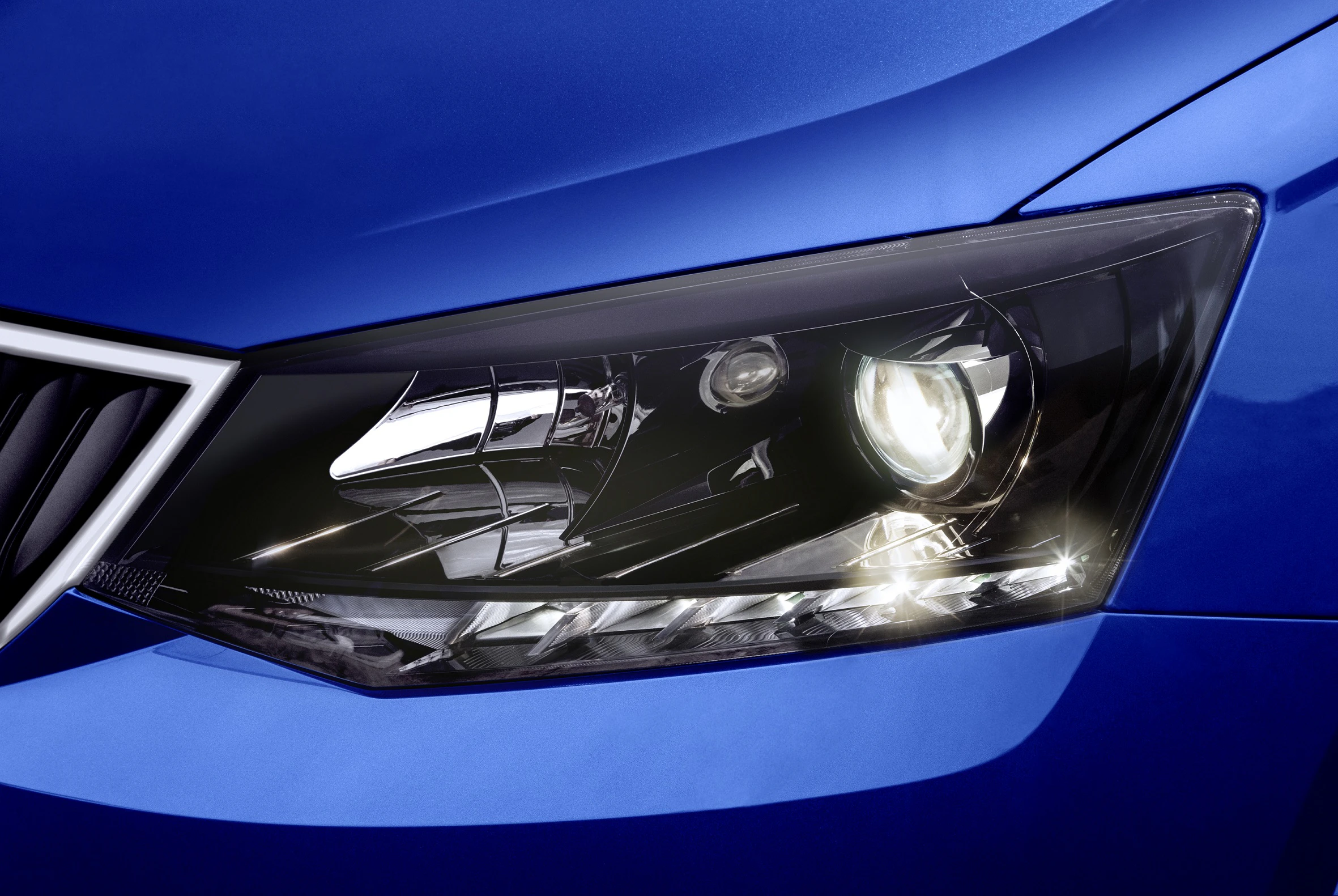 Nahaufnahme eines blauen Autoscheinwerfers mit klaren Details und leuchtender Lampe.