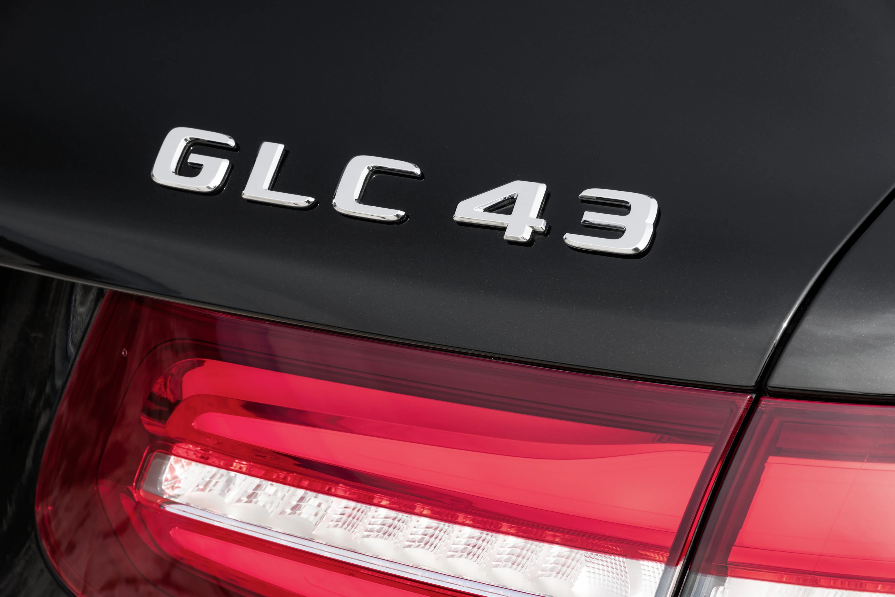 Nahaufnahme des Rücklichts und des Emblems "GLC 43" auf einem schwarzen Auto.