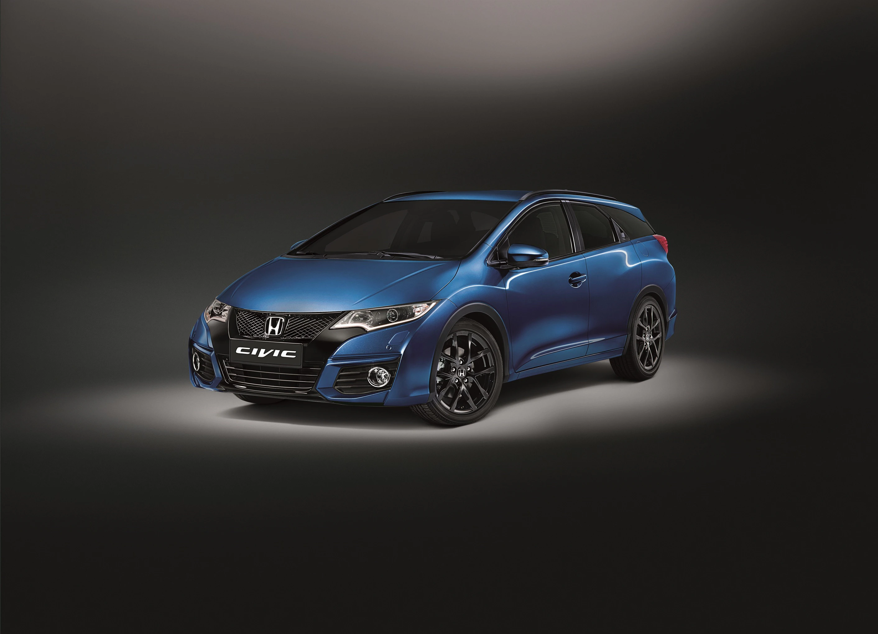 Blauer Honda Civic Kombi auf einem dunklen Hintergrund, von vorne schräg rechts fotografiert, mit sportlichem Design und glänzenden Details.