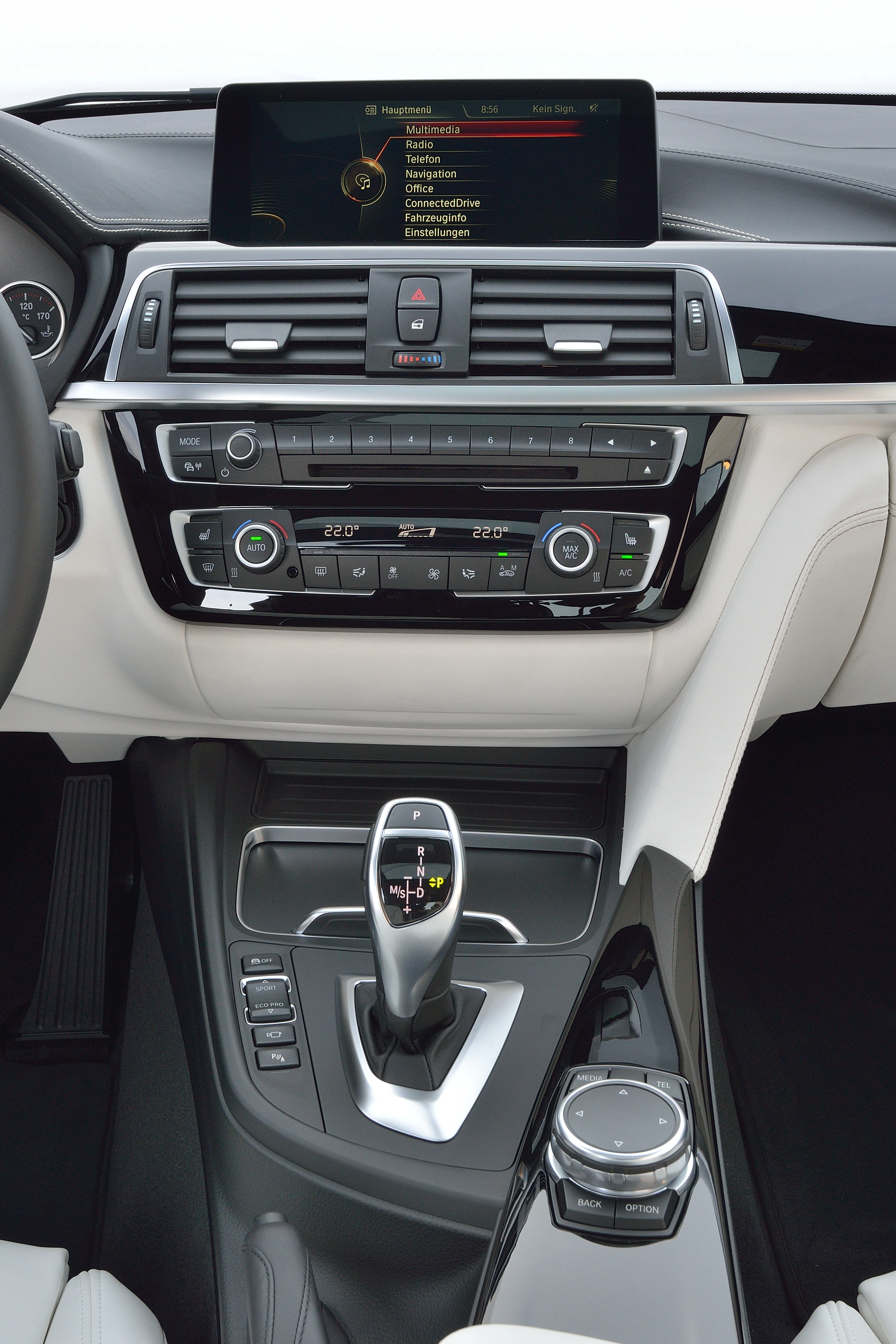Innenraum eines Autos mit Fokus auf Infotainment-System, Klimaanlage und Automatikschalthebel. Modernes und stilvolles Design in Schwarz und Weiß.