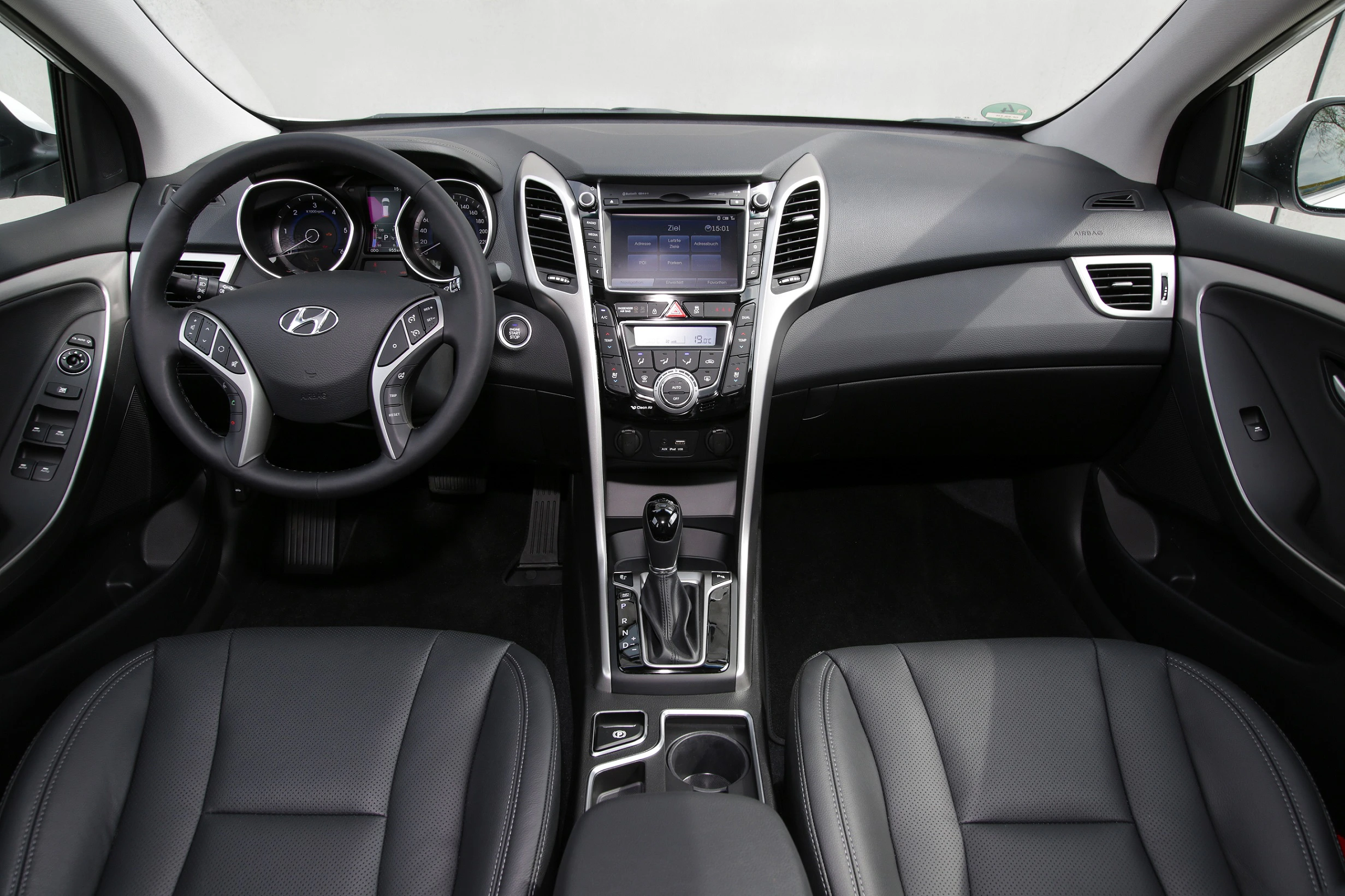 Innenraum eines modernen Autos mit schwarzer Lederausstattung, multifunktionalem Lenkrad und zentralem Display auf der Mittelkonsole.
