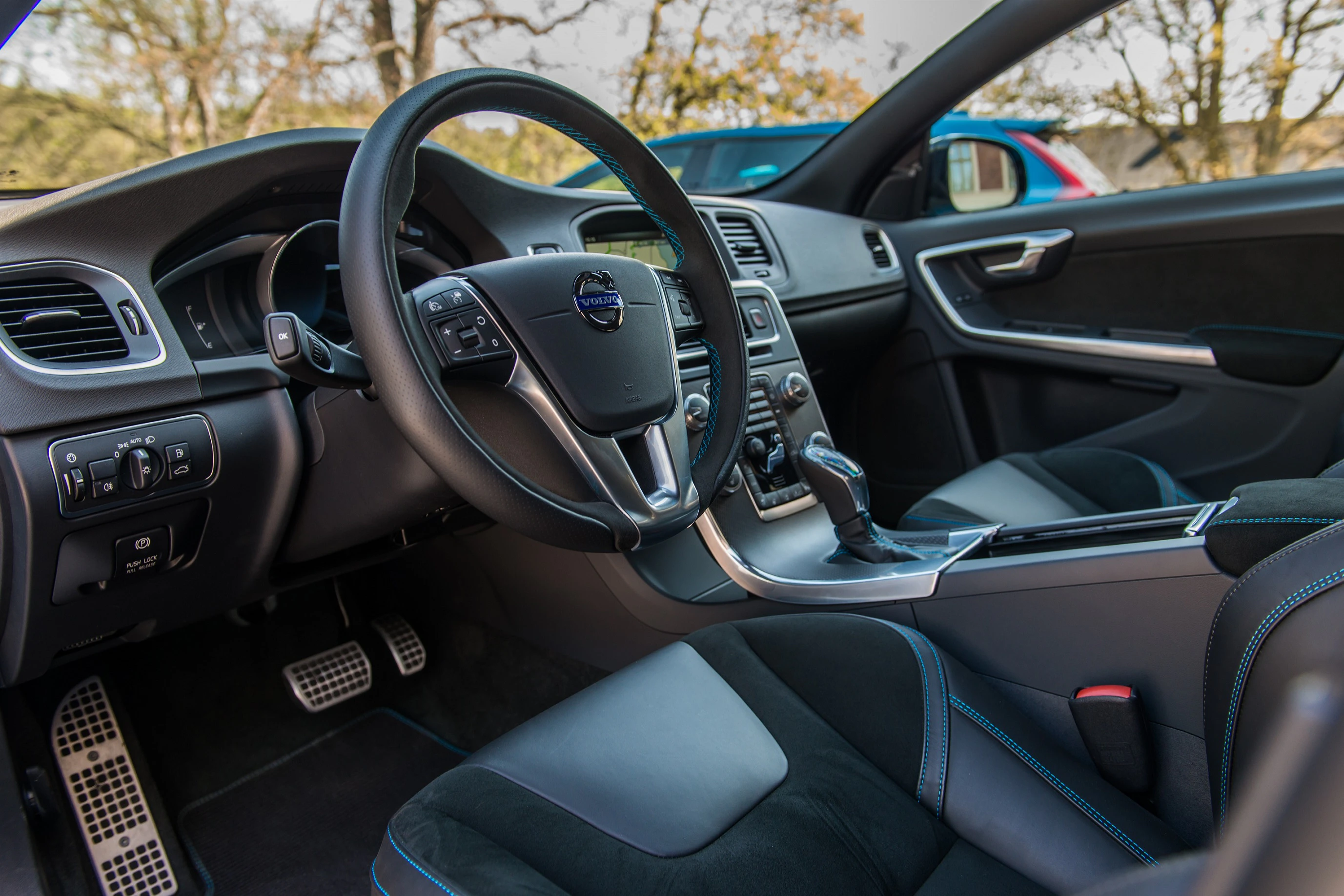 Innenraum eines modernen Autos, dunkle Ledersitze, Multifunktionslenkrad, Touchscreen-Display auf der Mittelkonsole, Tageslicht im Hintergrund.
