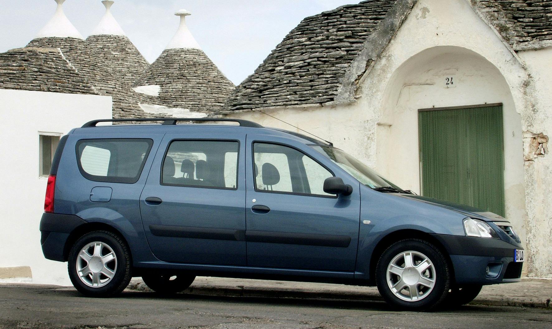 Blauer Kombi parkt vor historischen Gebäuden mit konischen Dächern und weiß gestrichenen Wänden.