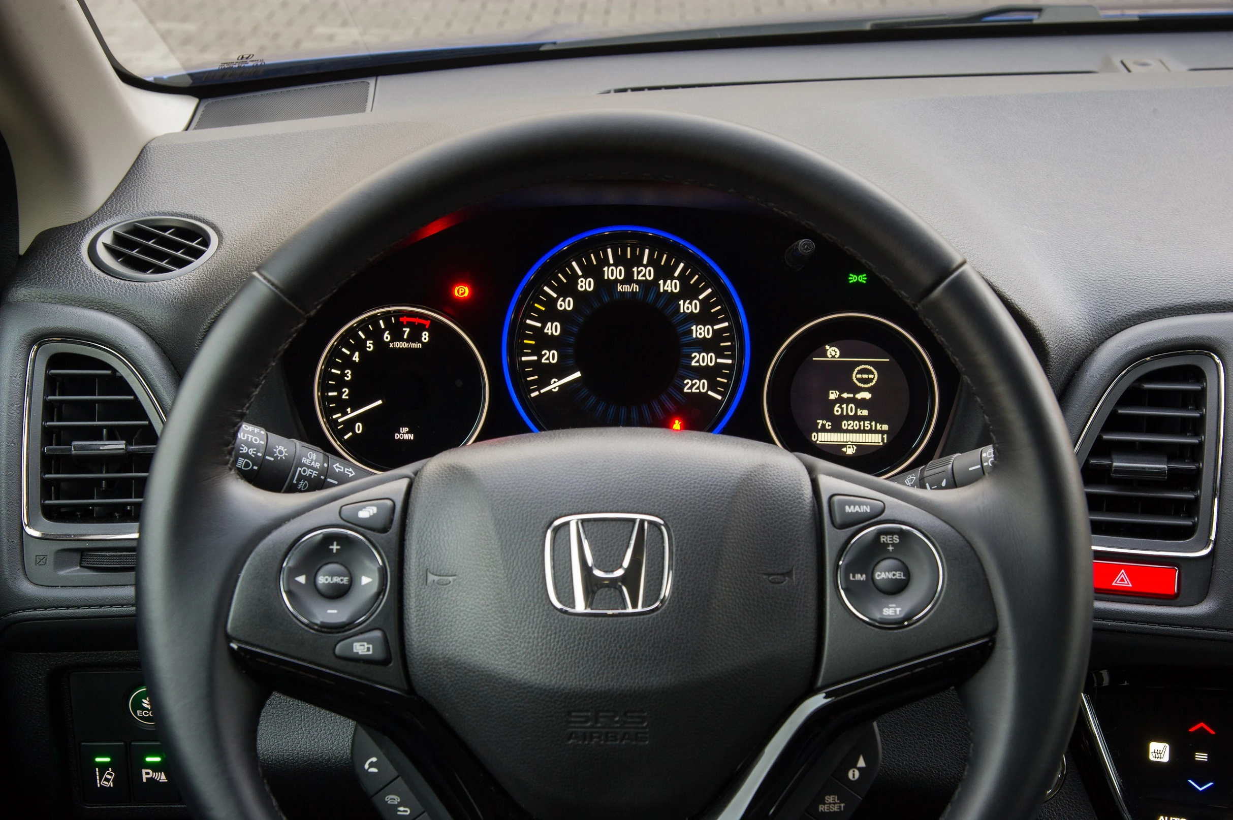 Lenkrad eines Honda mit sichtbarem Tacho, Tachometer und verschiedenen Anzeigen und Symbolen im Armaturenbrett.