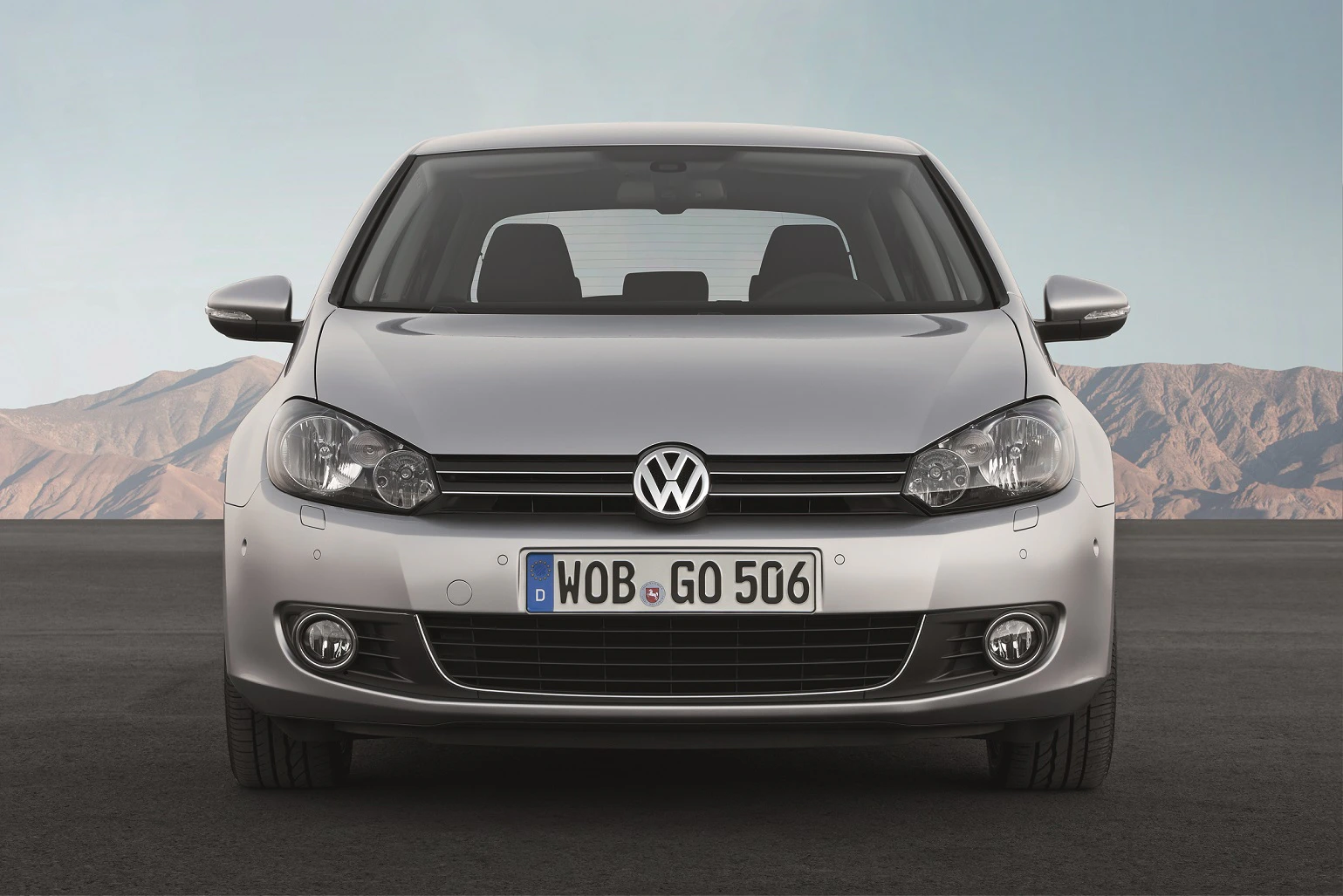 Silberner VW Golf VI, fotografiert frontal vor einer Berglandschaft unter klarem Himmel. Deutsche Nummernschild sichtbar.