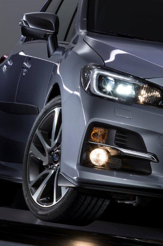 Silbergraues Auto in Nahaufnahme, zeigt Scheinwerfer und Vorderrad, mit reflektierender Oberfläche und glänzendem Lack.