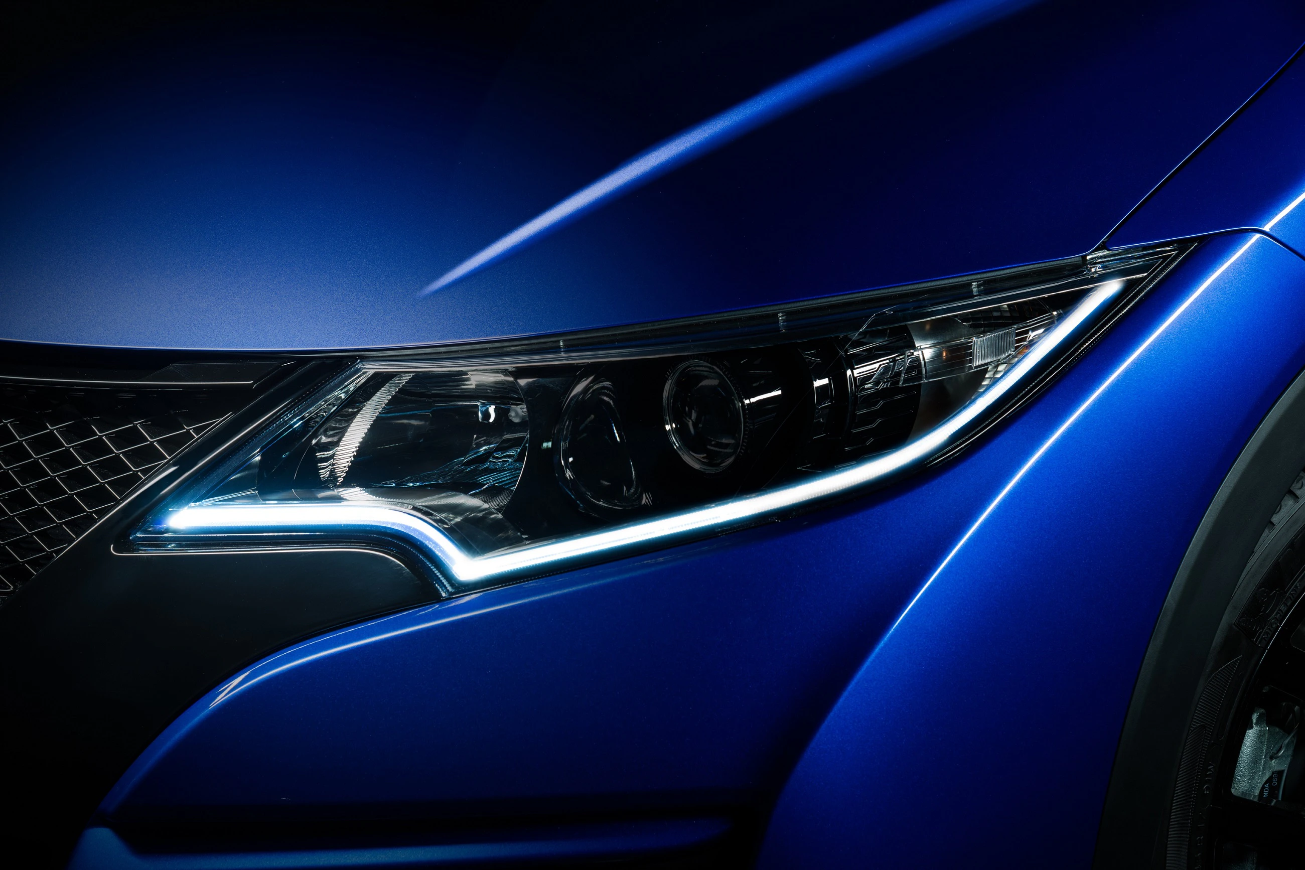 Nahaufnahme eines blauen Autoscheinwerfers mit modernem Design und LED-Leuchten, die scharf und glänzend erscheinen.