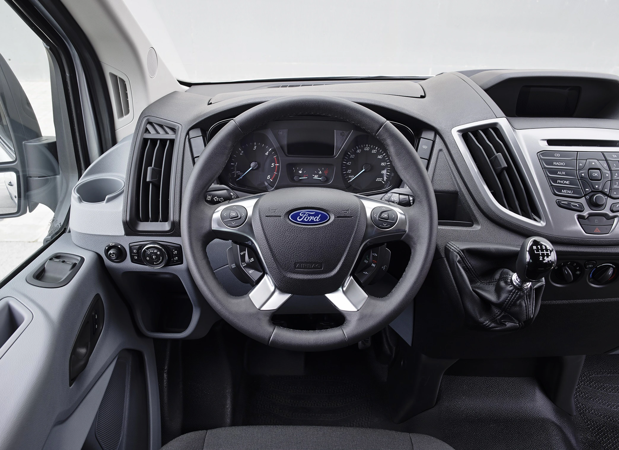 Cockpit eines Ford-Kleintransporters mit Lenkrad, Armaturenbrett, Schaltknauf und Mittelkonsole. Mehrere Bedienungselemente gut sichtbar.
