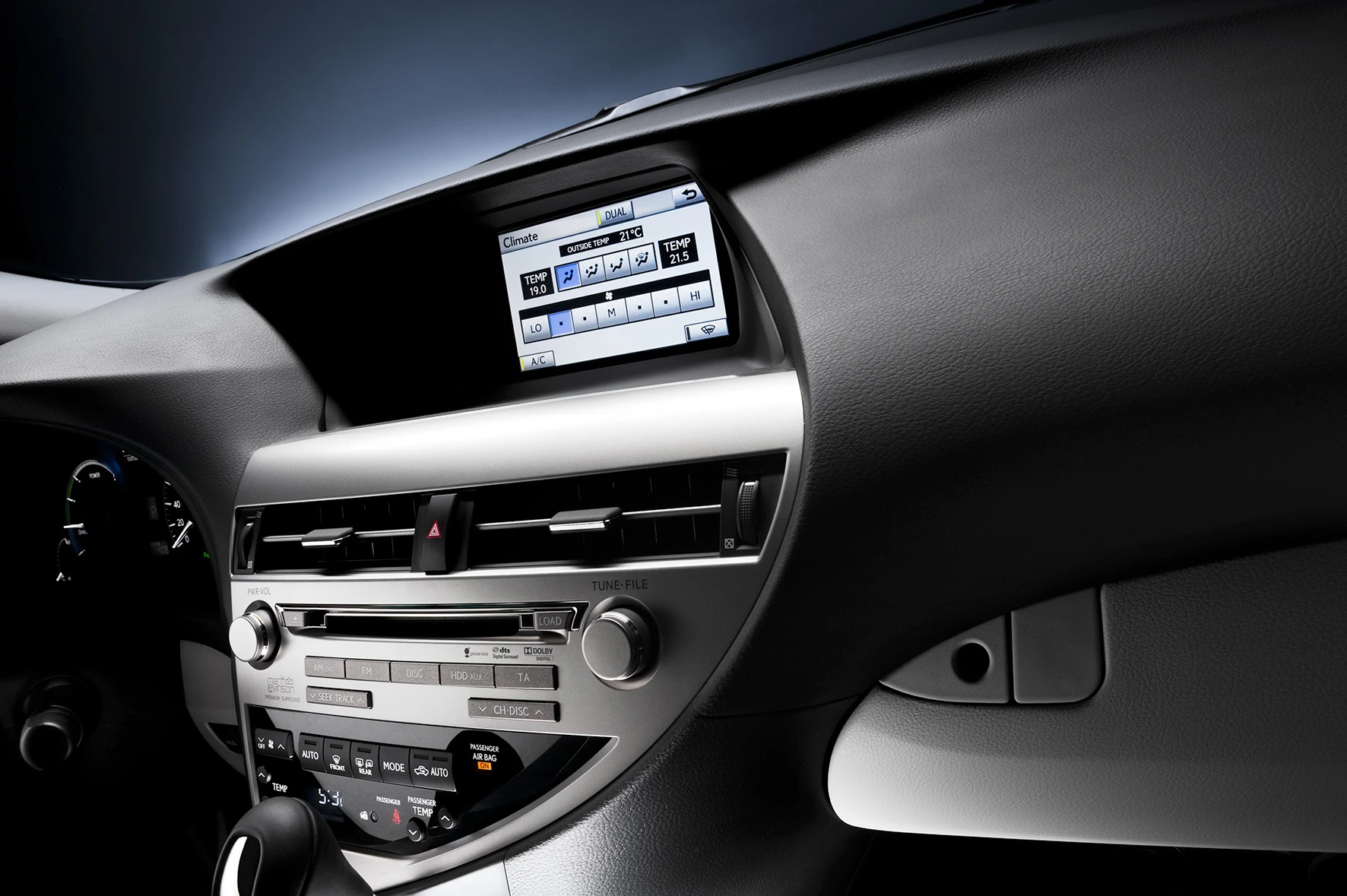 Nahaufnahme eines modernen Auto-Armaturenbretts mit Touchscreen-Bildschirm und Belüftungsschlitzen. Steuerknöpfe und Digitalanzeige sichtbar.