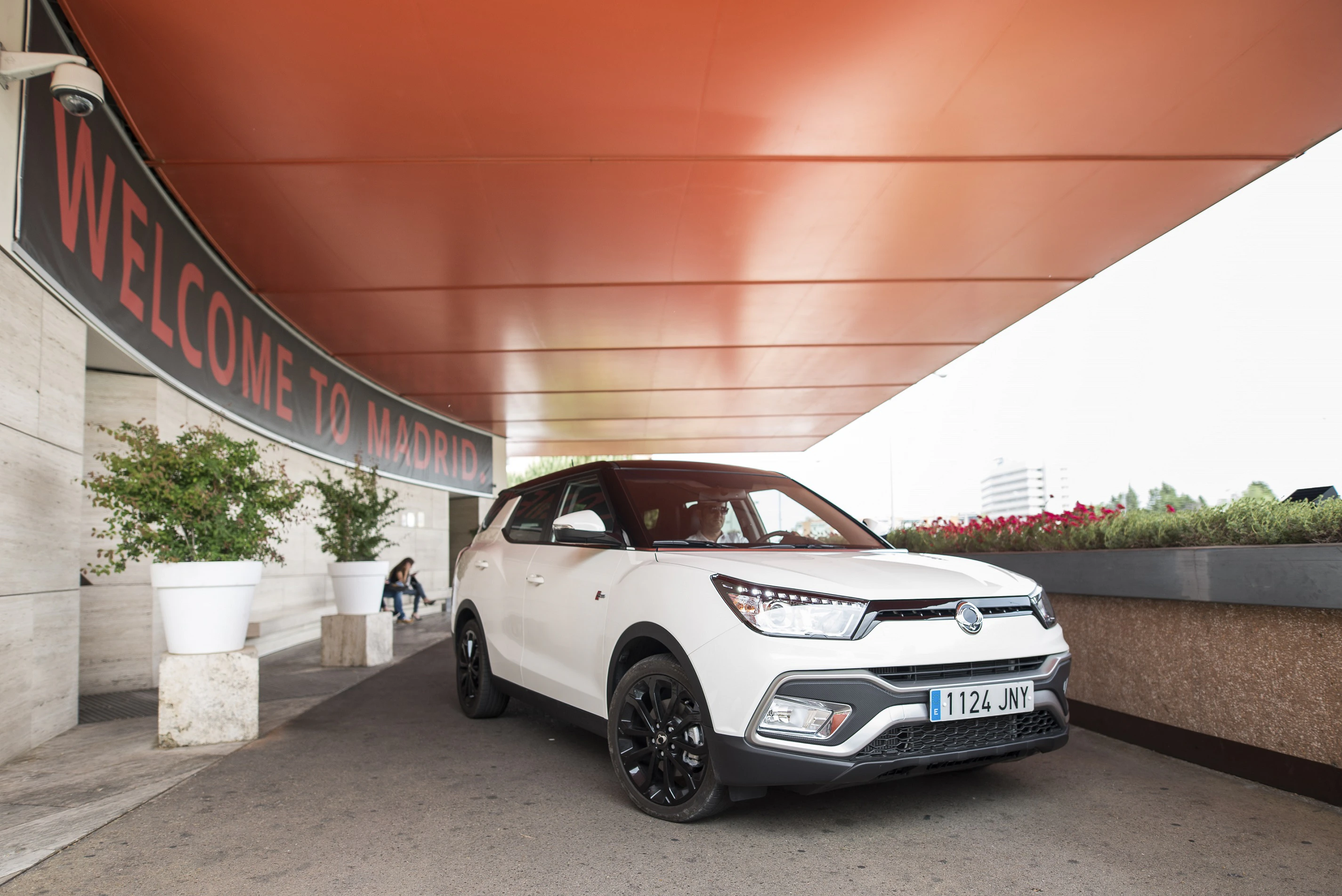 Weißer SUV steht unter einem Vordach mit der Aufschrift "Welcome to Madrid".
