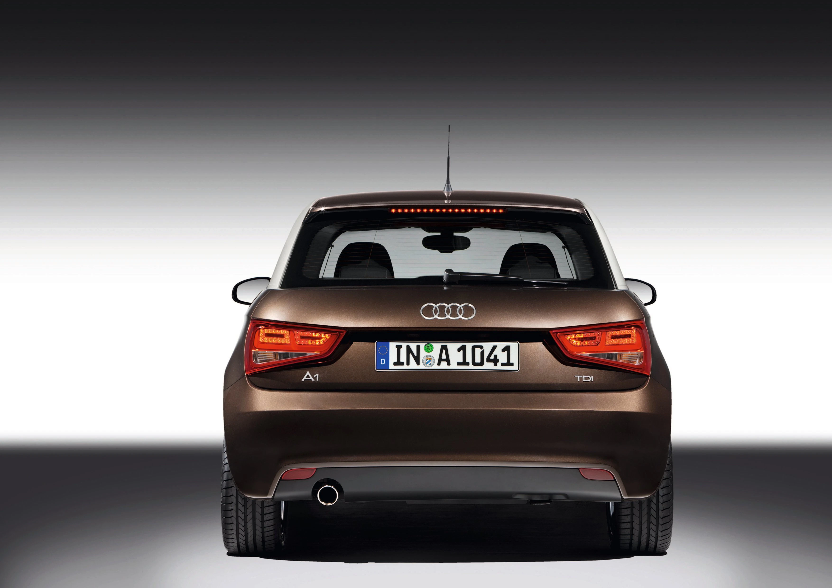 Rückansicht eines braunen Audi A1 mit deutschem Kennzeichen. Rechteckige Rücklichter und ein Auspuffrohr auf der linken Seite.