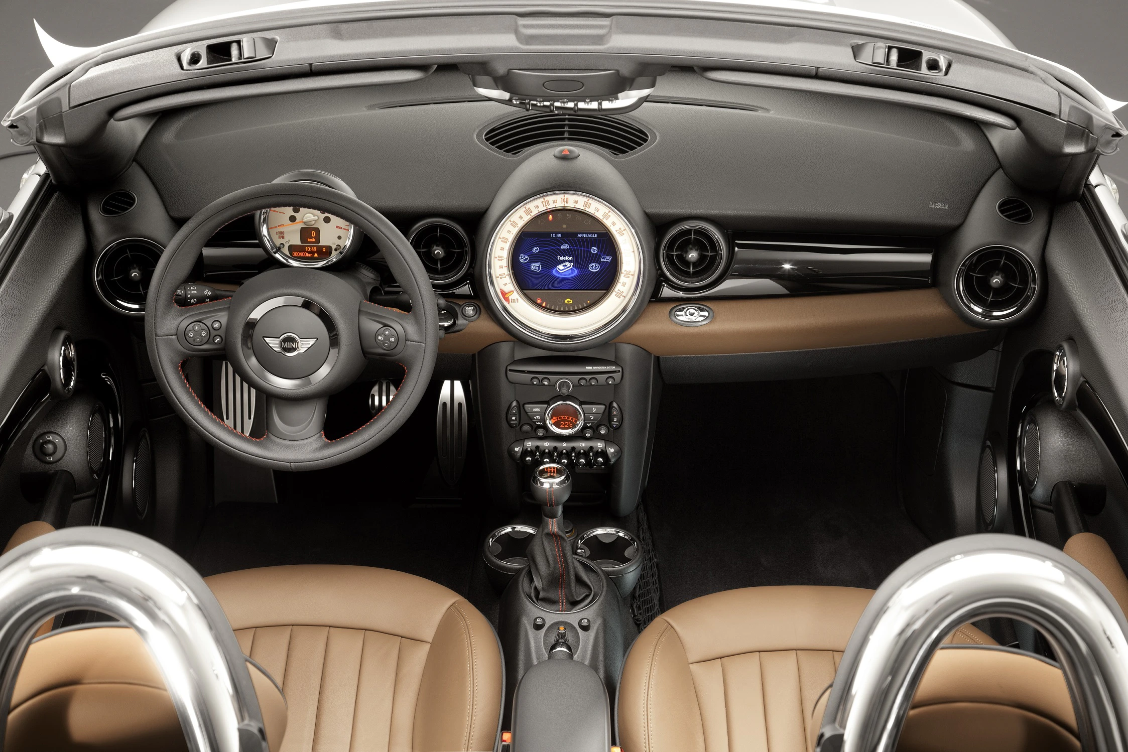 Innenraum eines Autos mit braunen Ledersitzen, modernem Armaturenbrett, großem Rundinstrument in der Mitte und sportlichem Lenkrad.