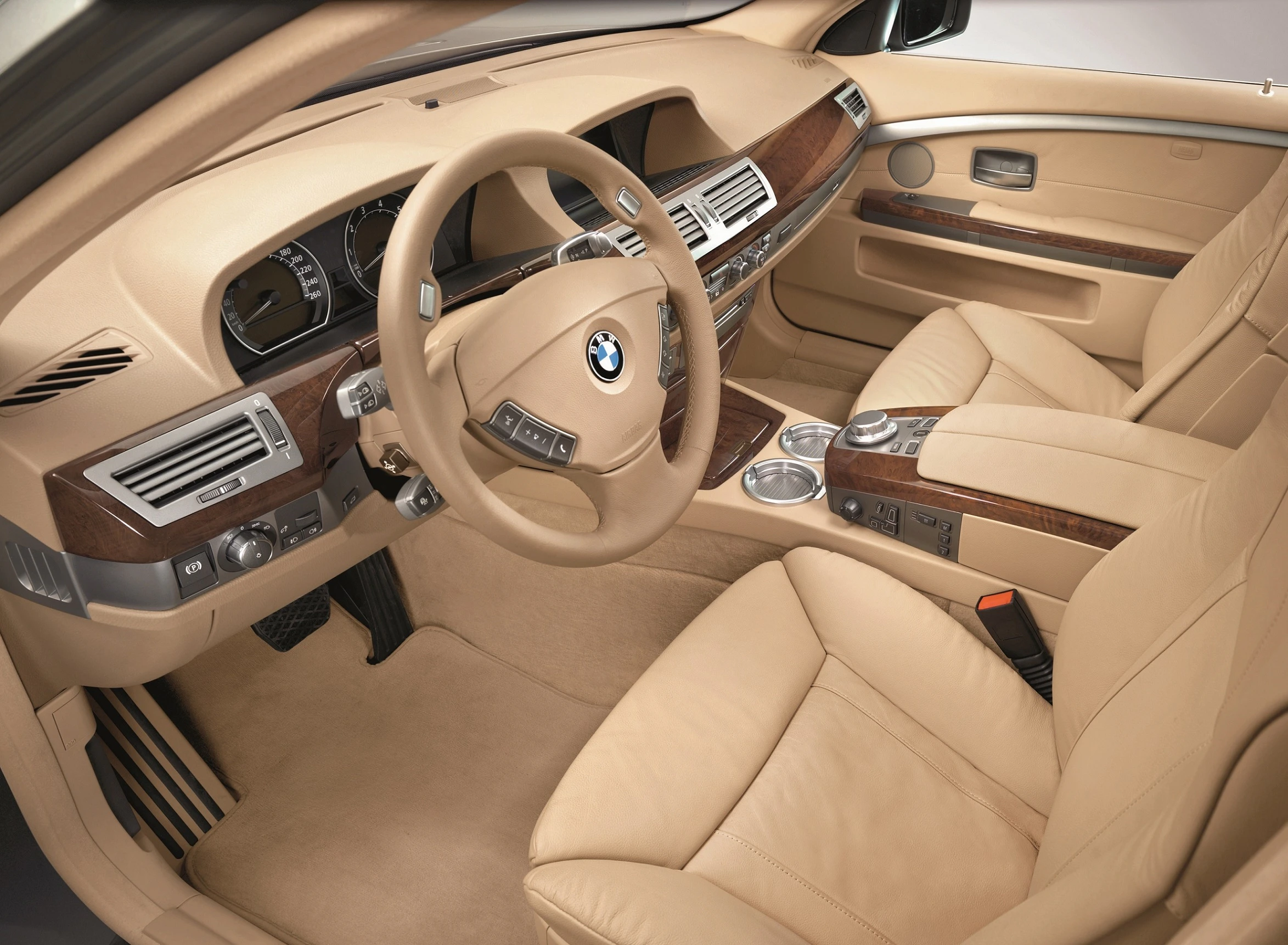 Innenraum eines Autos mit beigefarbenem Leder, Holzelementen, Lenkrad und Armaturenbrett eines BMW-Modells.