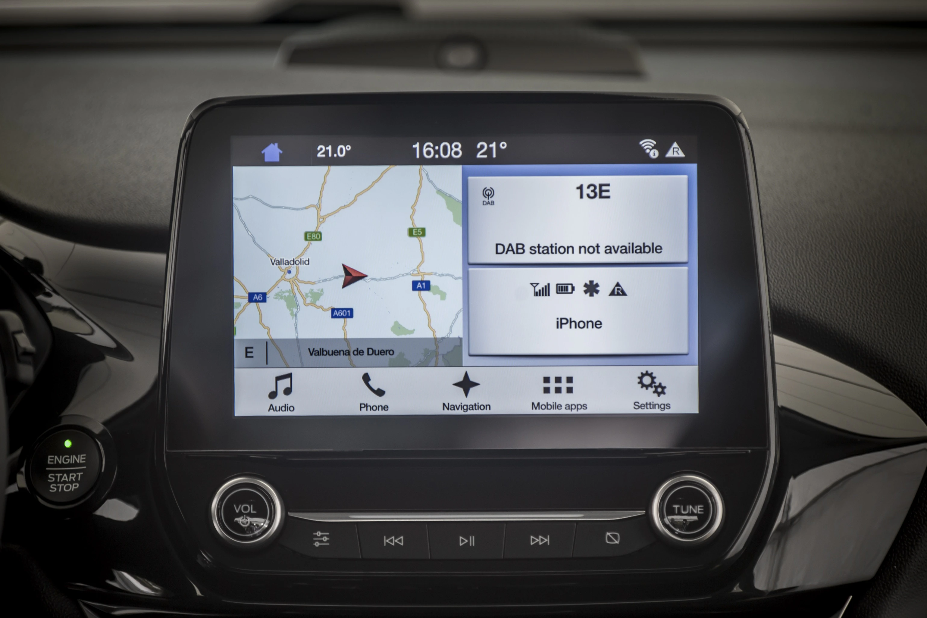 Navigationssystem eines Autos zeigt eine Karte mit Route an. Bildschirm enthält Uhrzeit, Wetter, und iPhone-Verbindungsinformation.