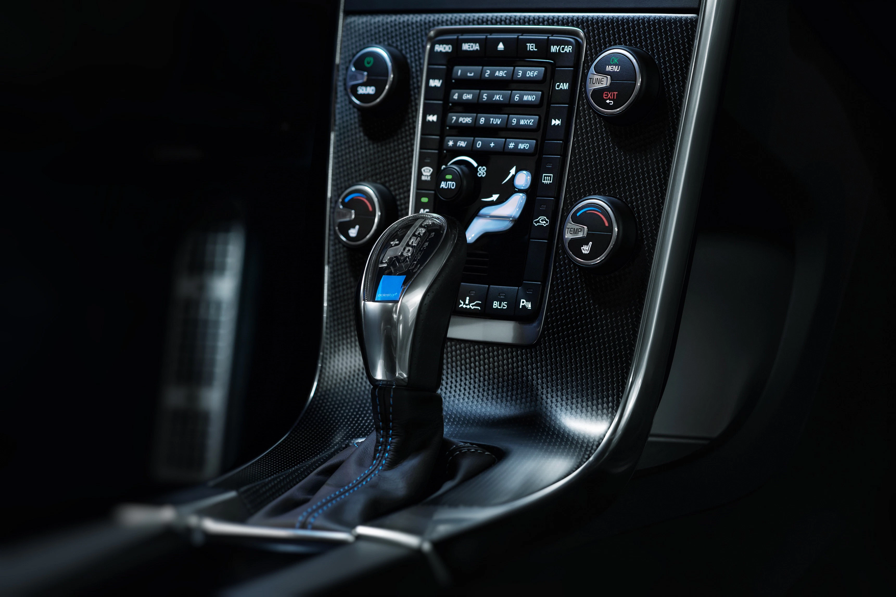 Nahaufnahme eines modernen Automatikgetriebeschalthebels in einem Auto mit einem zentralen Bedienfeld und diversen Knöpfen und Reglern.