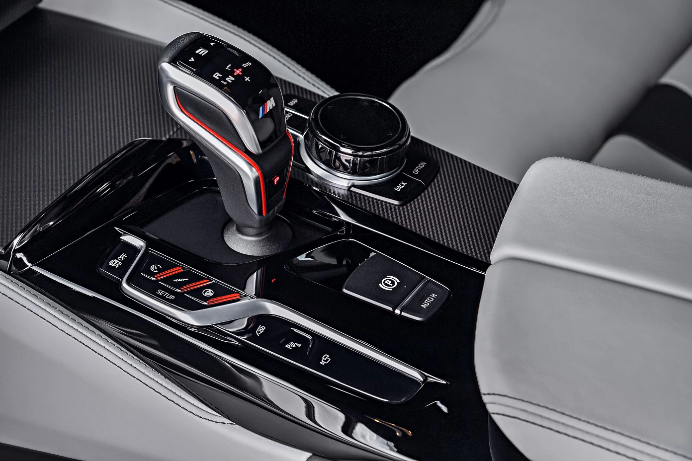 Nahaufnahme eines modernen Automatikgetriebes in einem Auto mit schwarzem und grauem Interieur, umgeben von Knöpfen und Drehreglern.