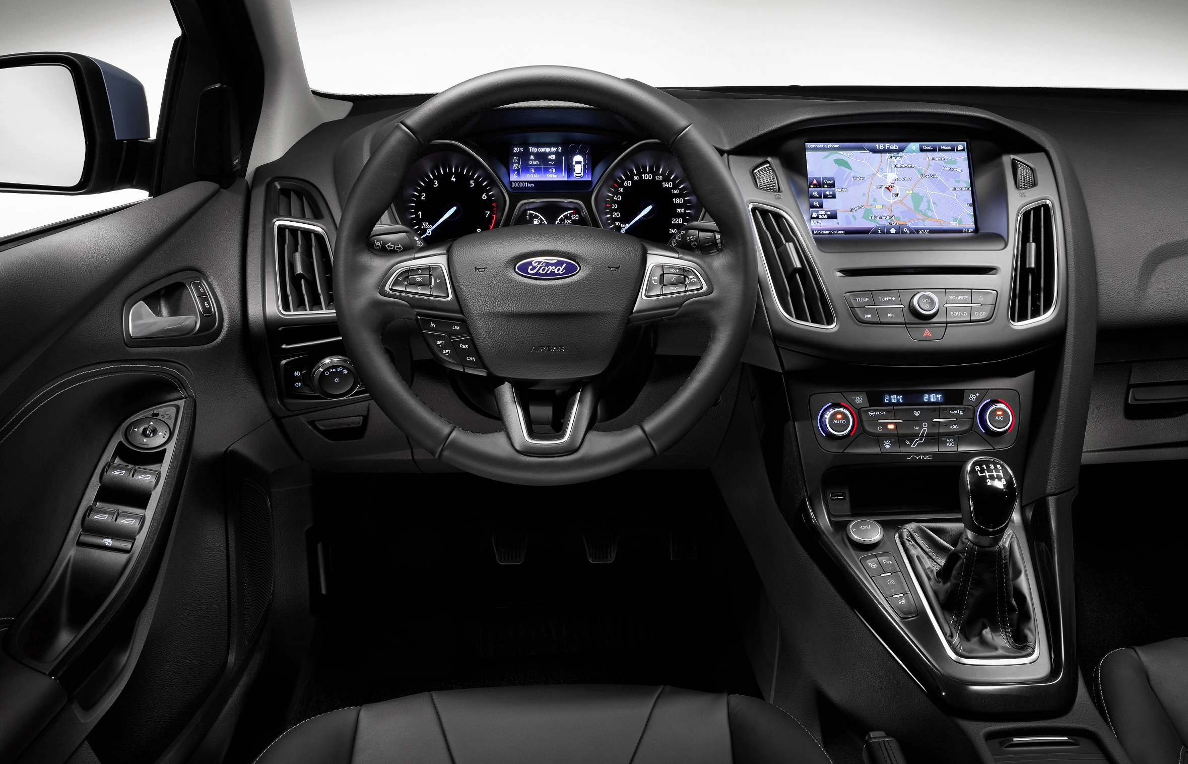 Innenraum eines Autos mit Lenkrad, Touchscreen-Navigationssystem, Schalthebel und zahlreichen Bedienelementen. Luxuriöses, modernes Design.