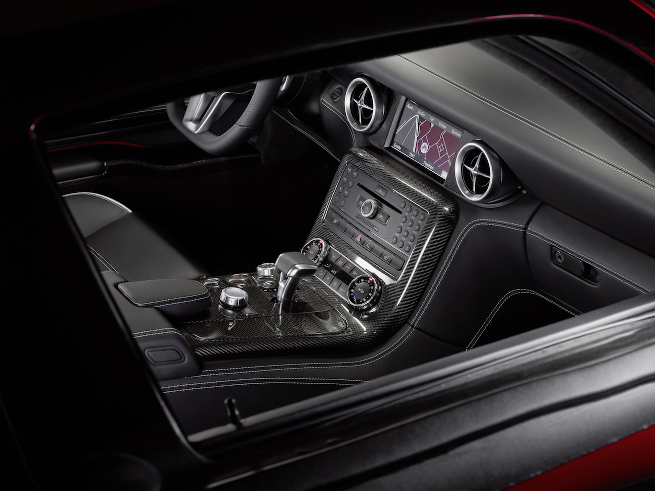 Nahaufnahme eines Autoinnenraums mit schwarzem Leder, einem modernen Touchscreen und zahlreichen silbernen Bedienelementen auf der Mittelkonsole.