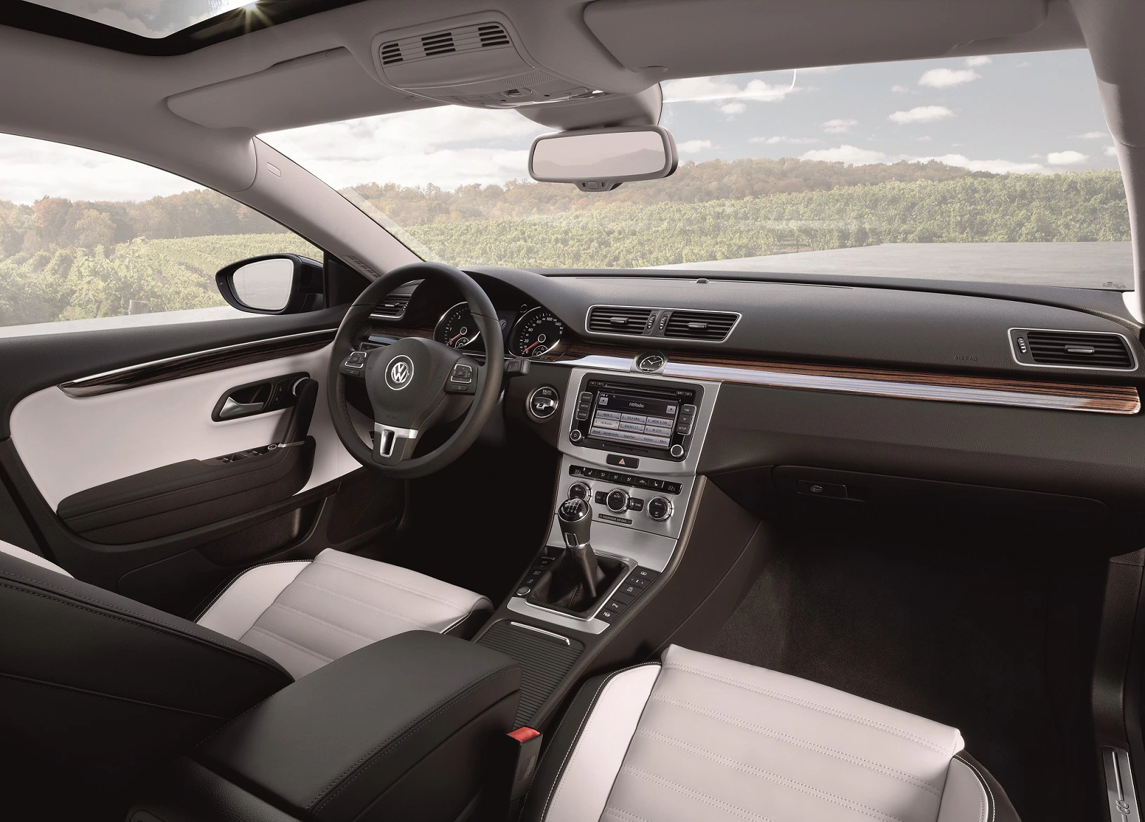 Innenraum eines modernen Autos mit schwarzer und weißer Lederausstattung, Holzverkleidung und einem großen Infotainment-Bildschirm.