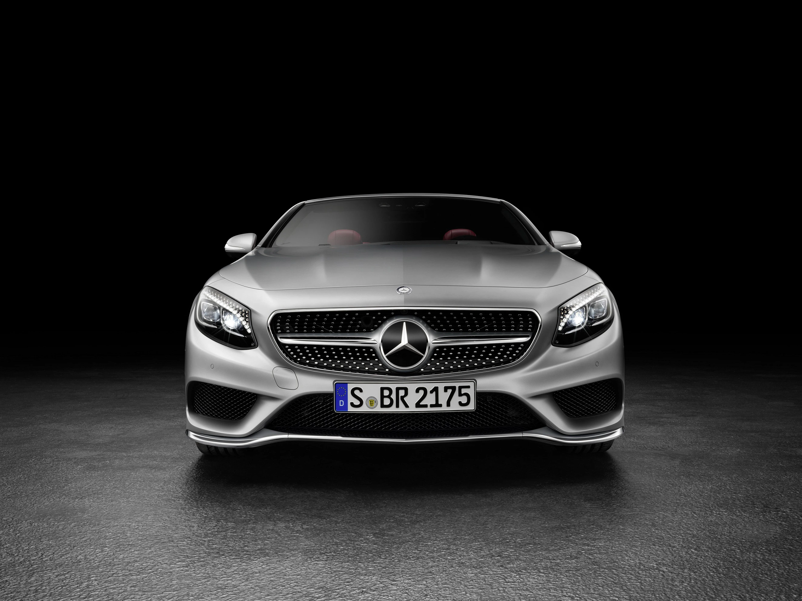 Silberner Mercedes-Benz, Frontansicht auf dunklem Hintergrund, mit markantem Kühlergrill und beleuchtetem Logo. Nummernschild: S BR 2175.