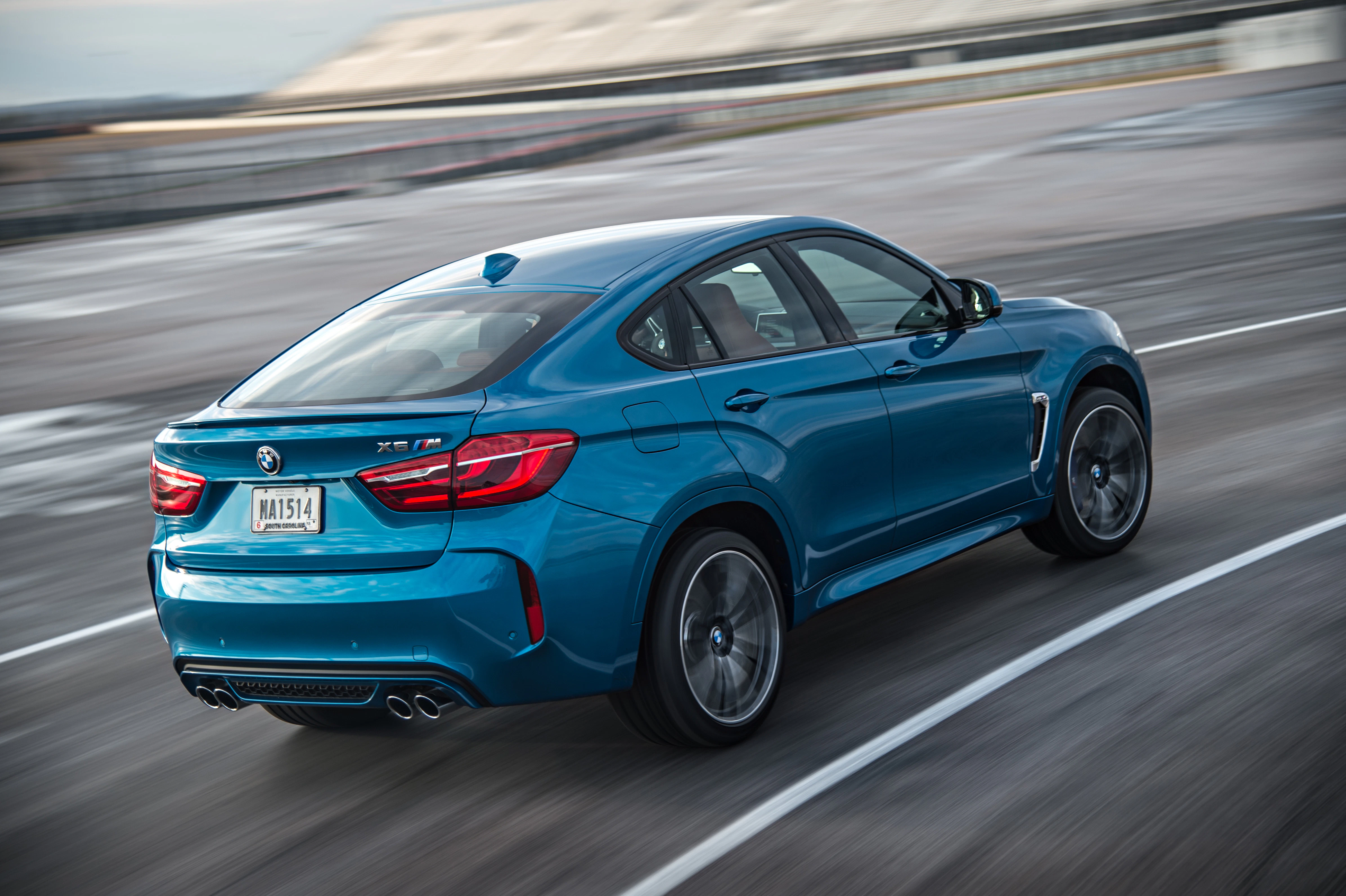 Blauer Sport-SUV fährt auf einer Rennstrecke. Dynamische Fahrt, Hinteransicht, verschwommener Hintergrund, kurviges Design, Betonoberfläche.