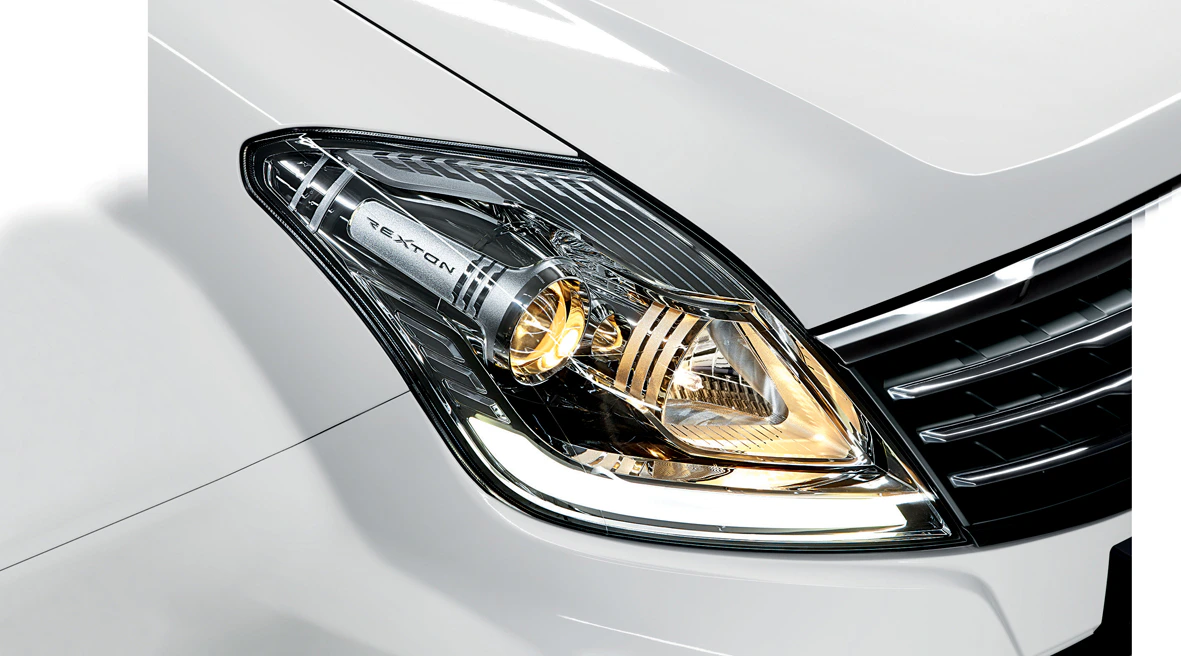 Nahaufnahme eines Autoscheinwerfers eines weißen Fahrzeugs. Das Licht ist eingeschaltet und es zeigt moderne Designlinien.